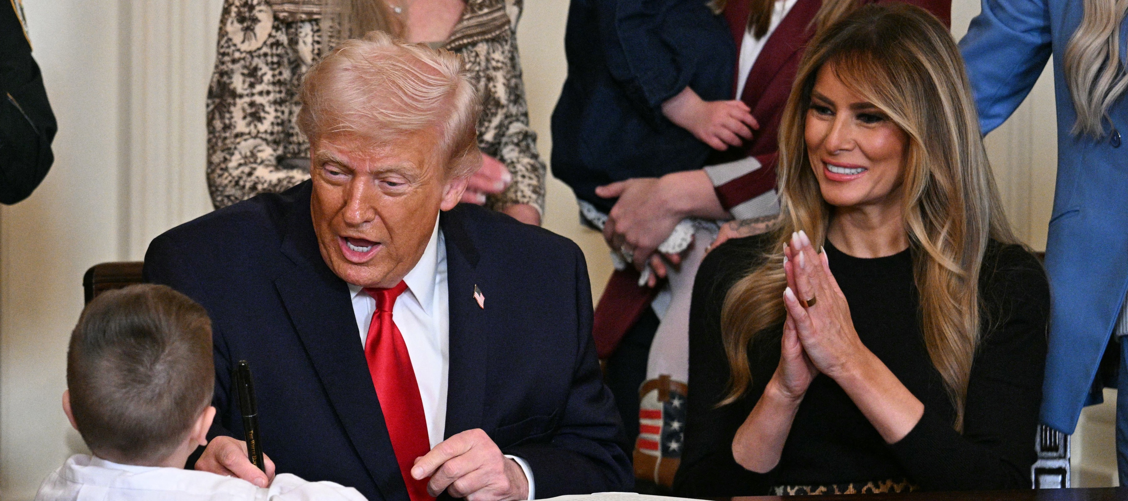 Donald and Melania Trump greet a child at the Resolute Desk in the Oval Office