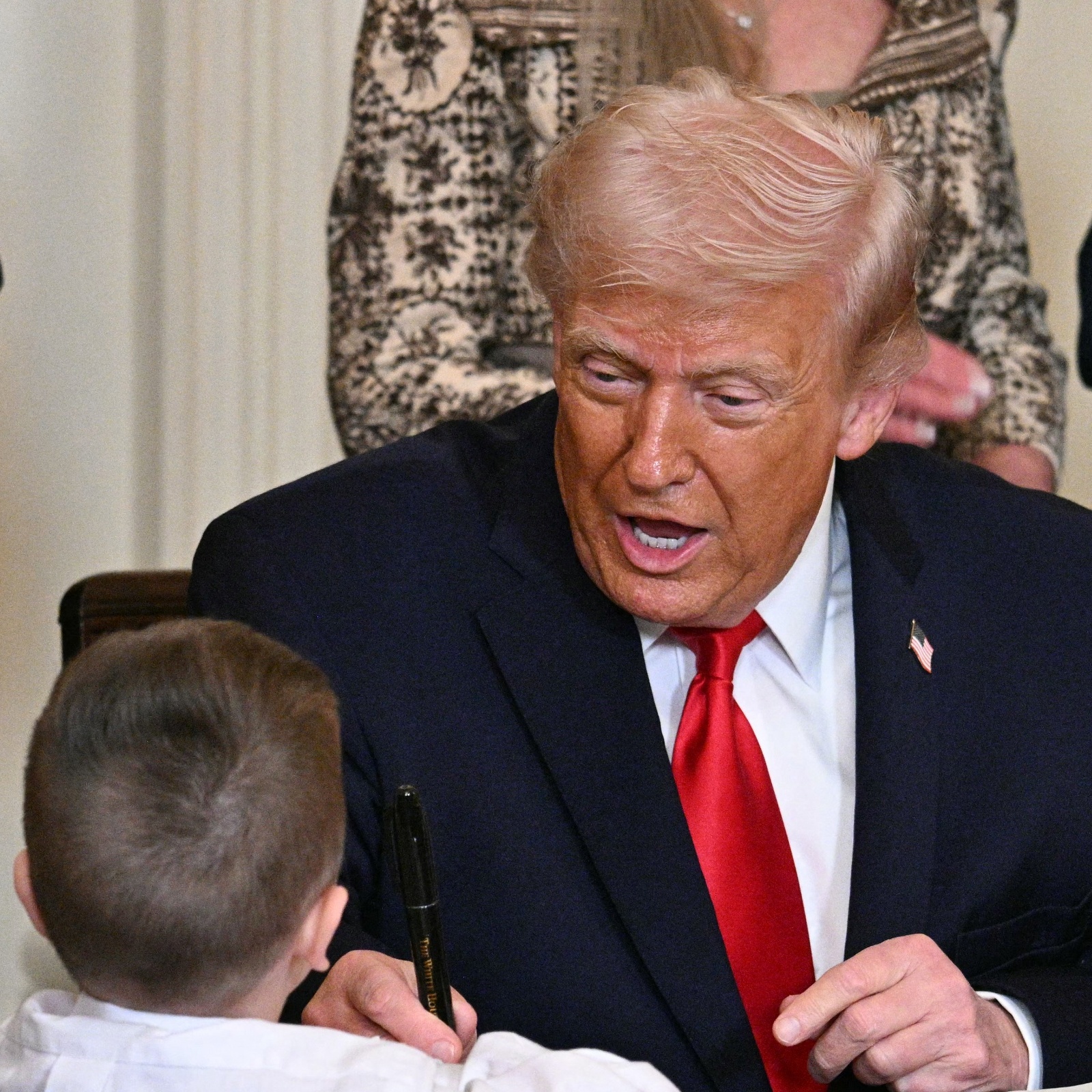 Donald and Melania Trump greet a child at the Resolute Desk in the Oval Office