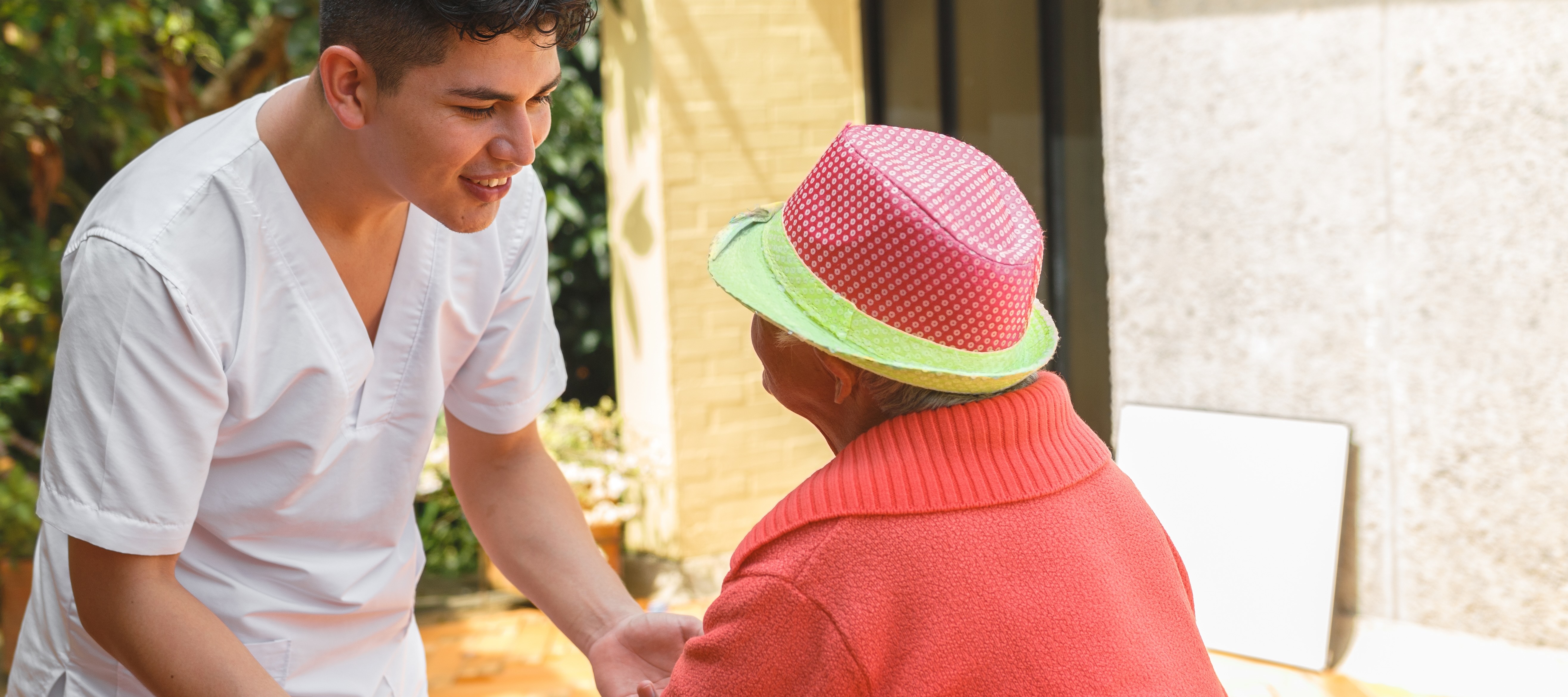 Young worker in nursing home helps senior woman
