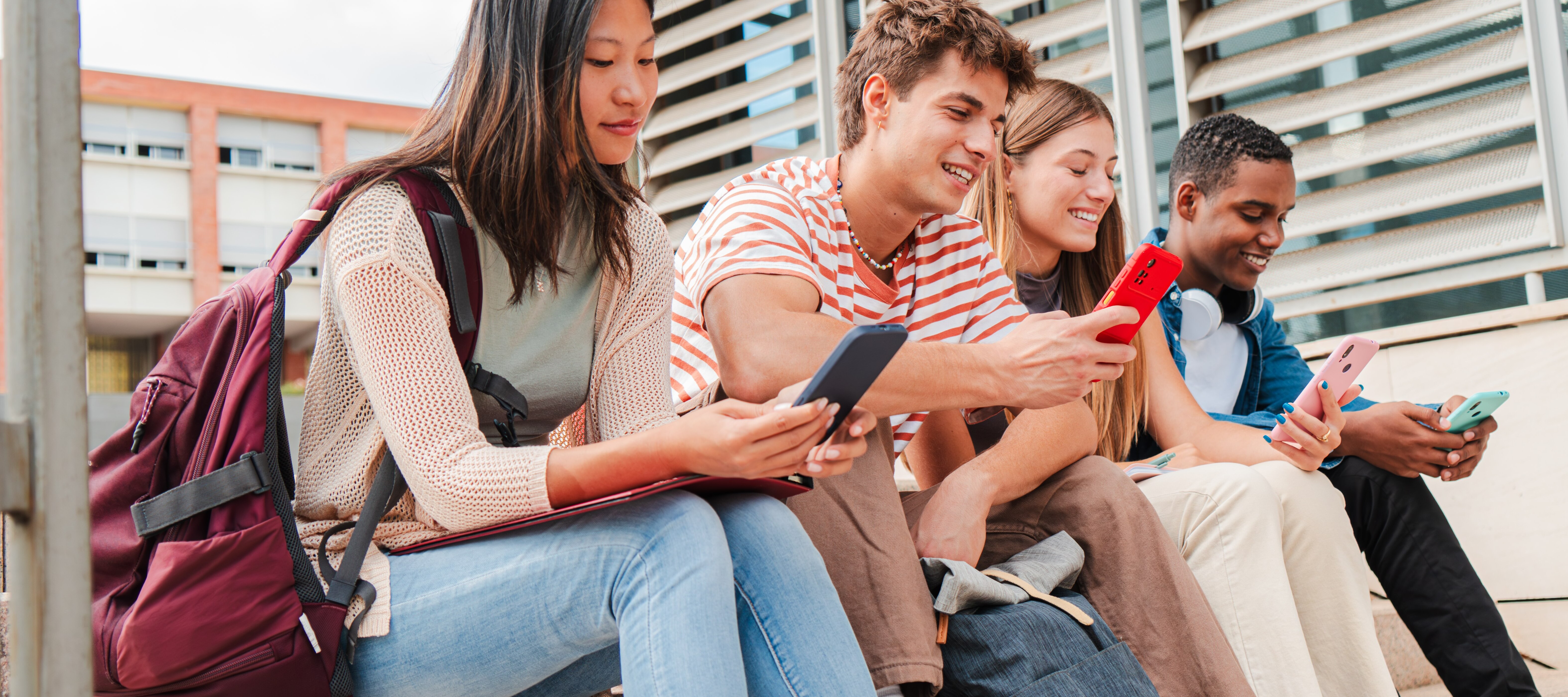 College students sitting outside on their smartphones