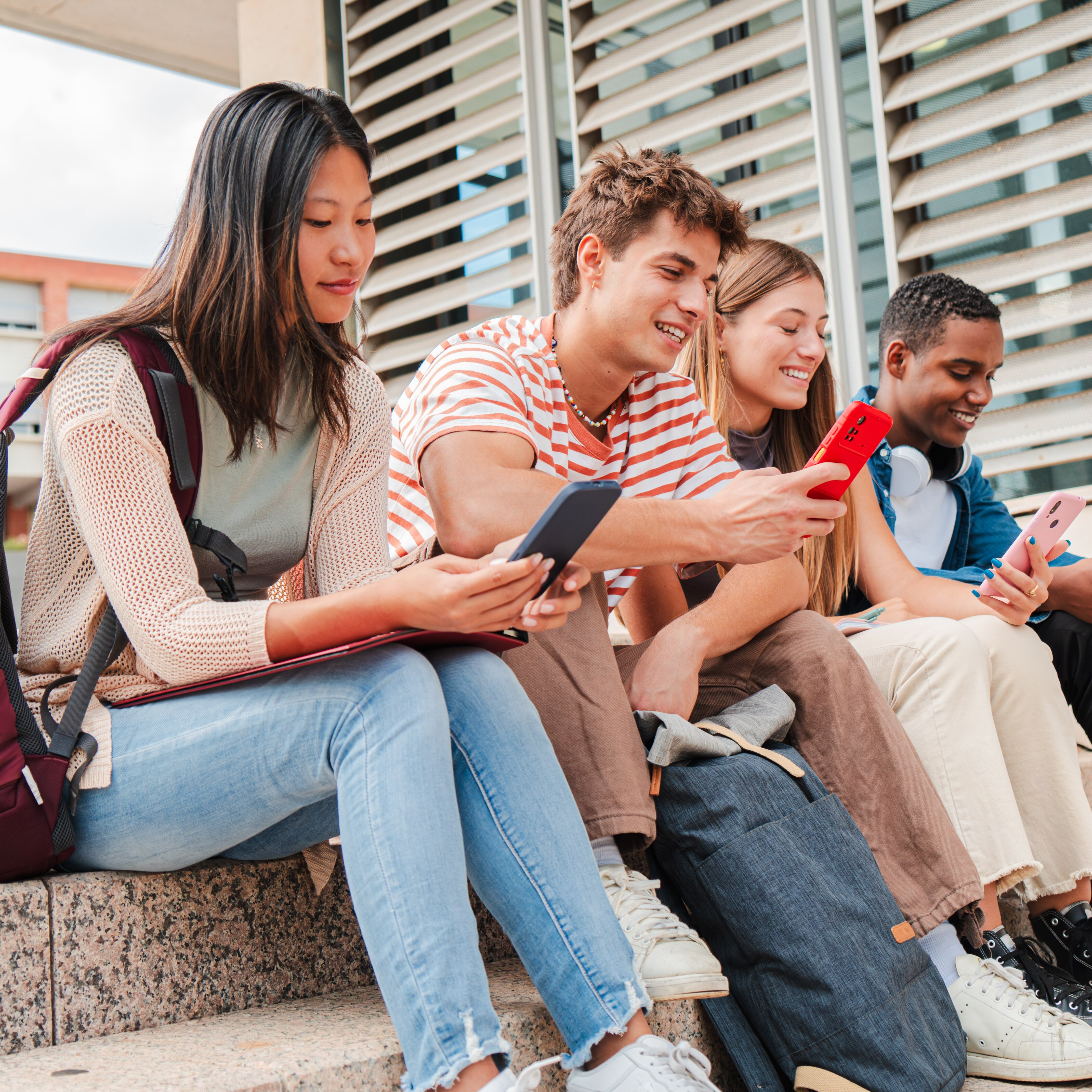 College students sitting outside on their smartphones
