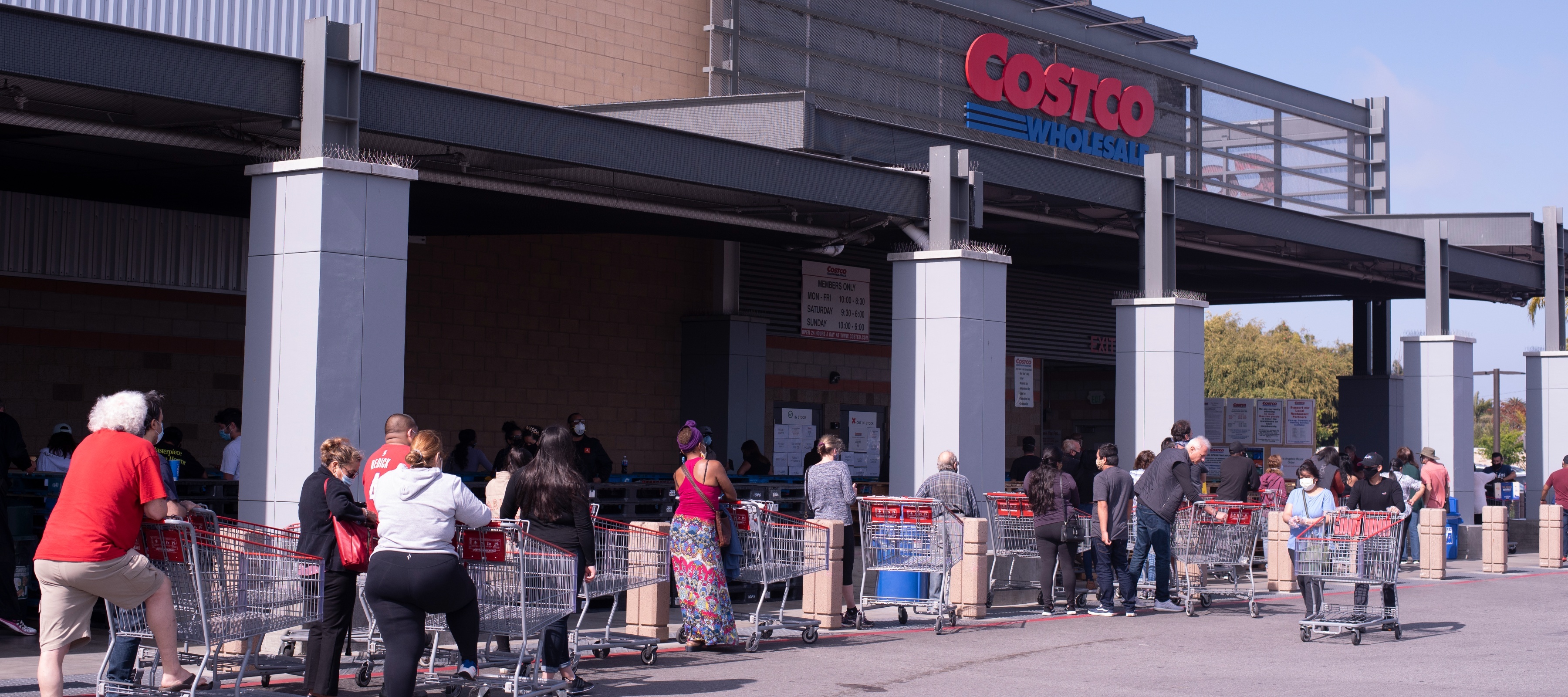 A line of people stand outside a Costco