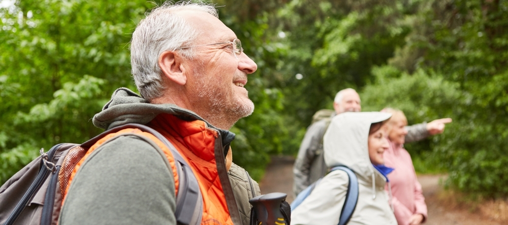 A group of four middle-aged people smiling on a hiking trail