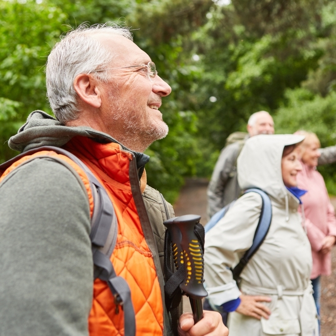A group of four middle-aged people smiling on a hiking trail