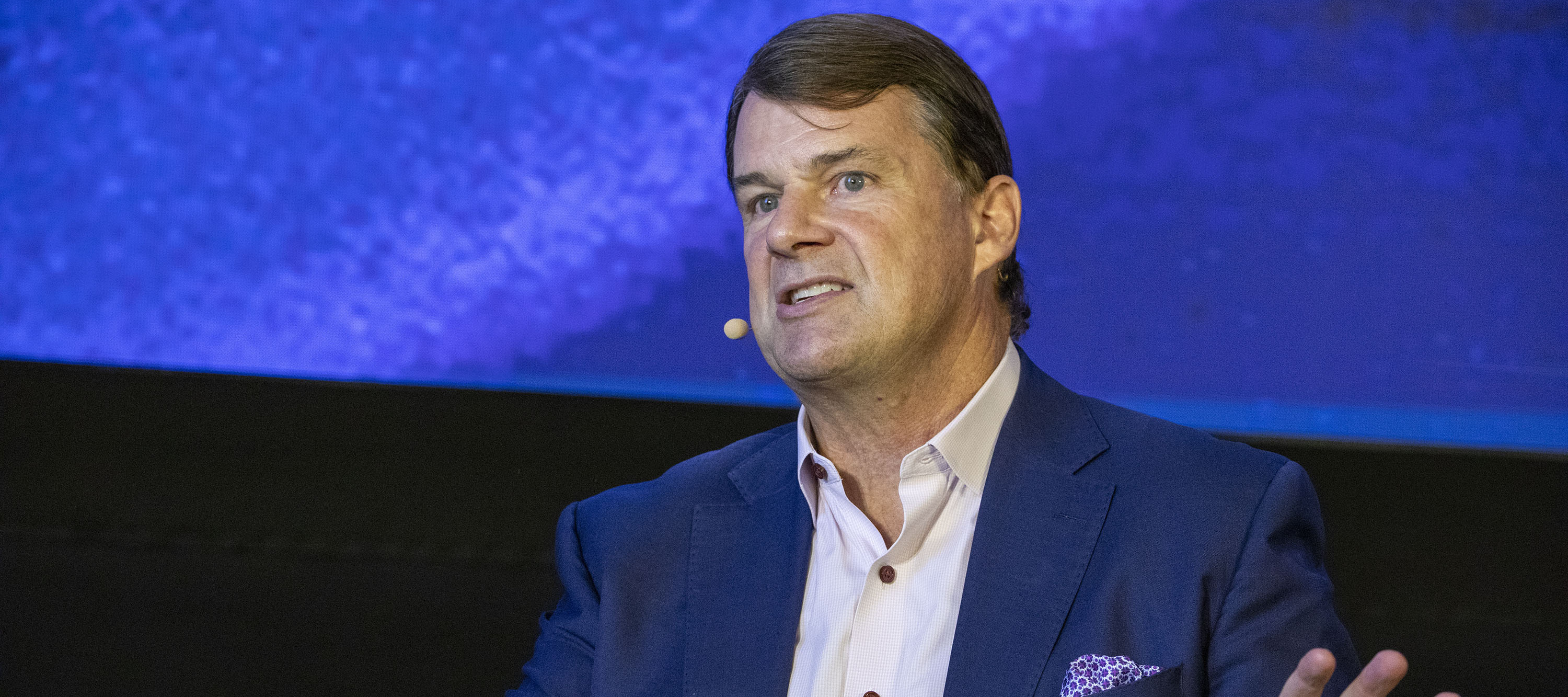 Ford CEO Jim Farley speaking at a conference with his hands waving.