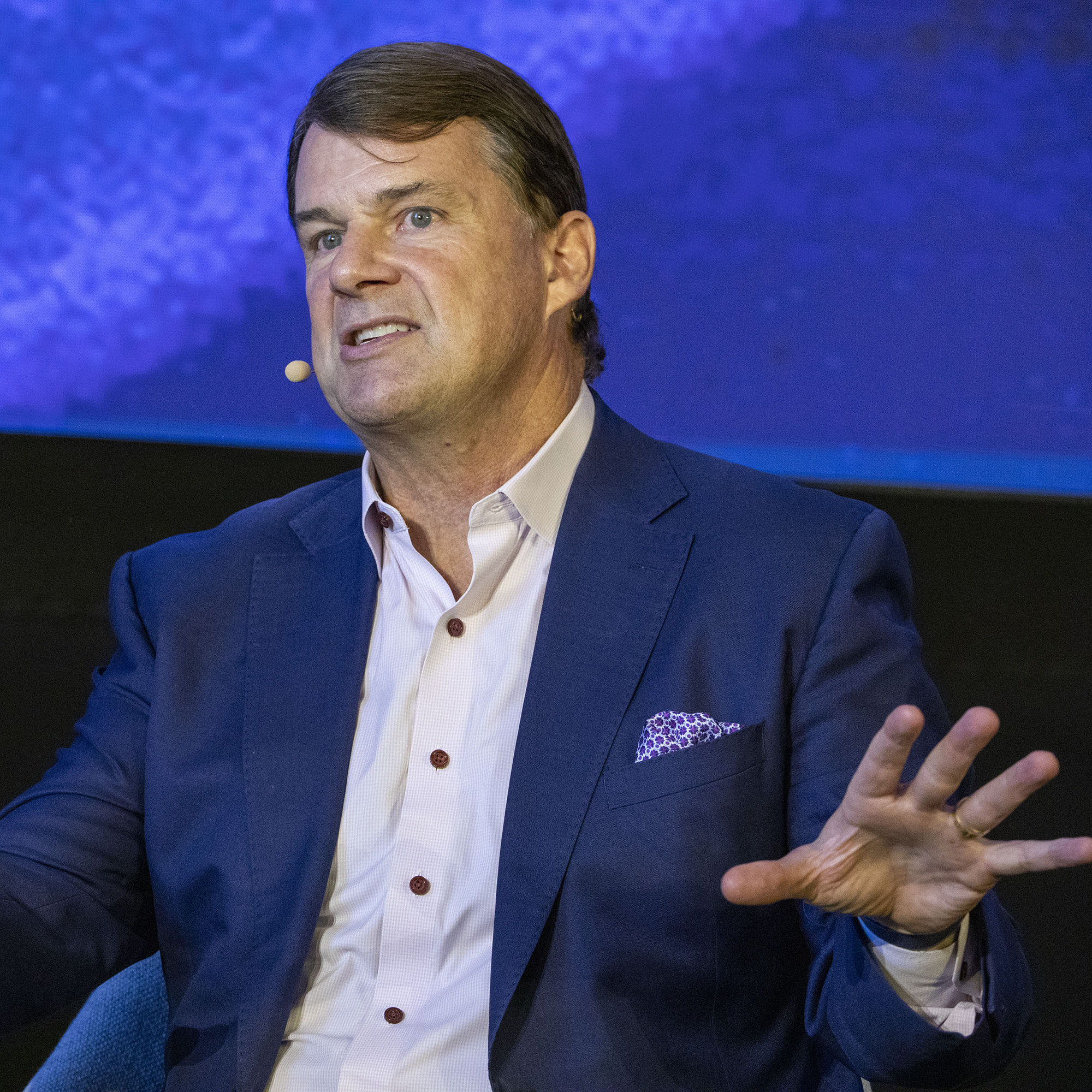 Ford CEO Jim Farley speaking at a conference with his hands waving.