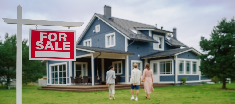 A photo of a house for sale and a couple visiting with a realtor