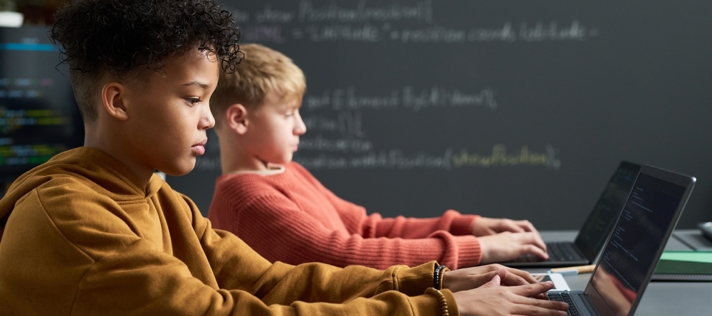 A photo of two male students using laptops in a classroom