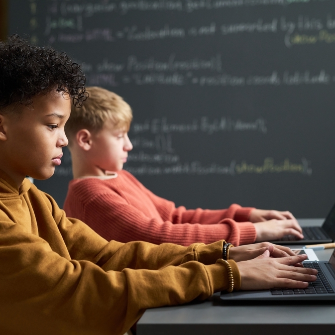 A photo of two male students using laptops in a classroom