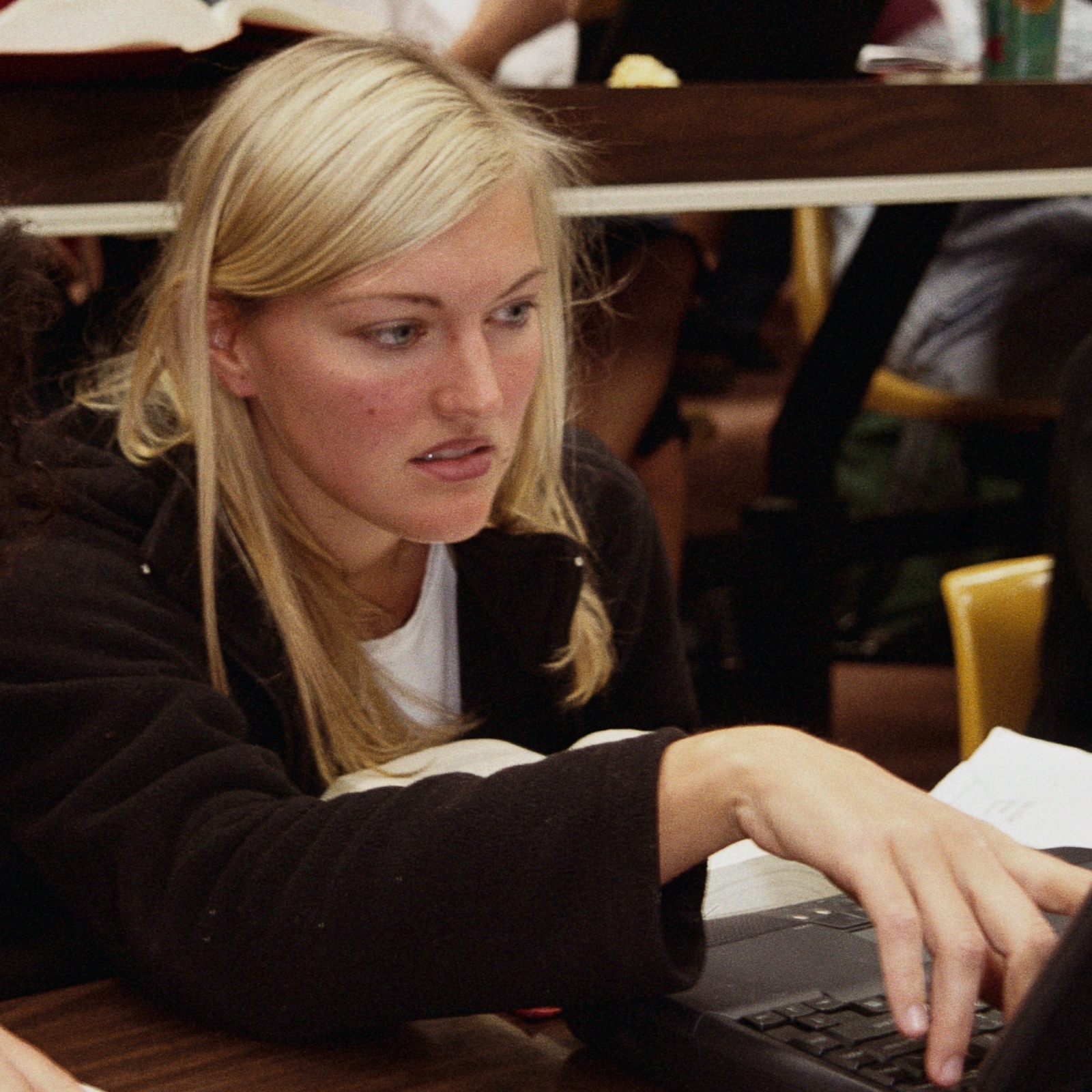 University students sit in a lecture hall on their laptops
