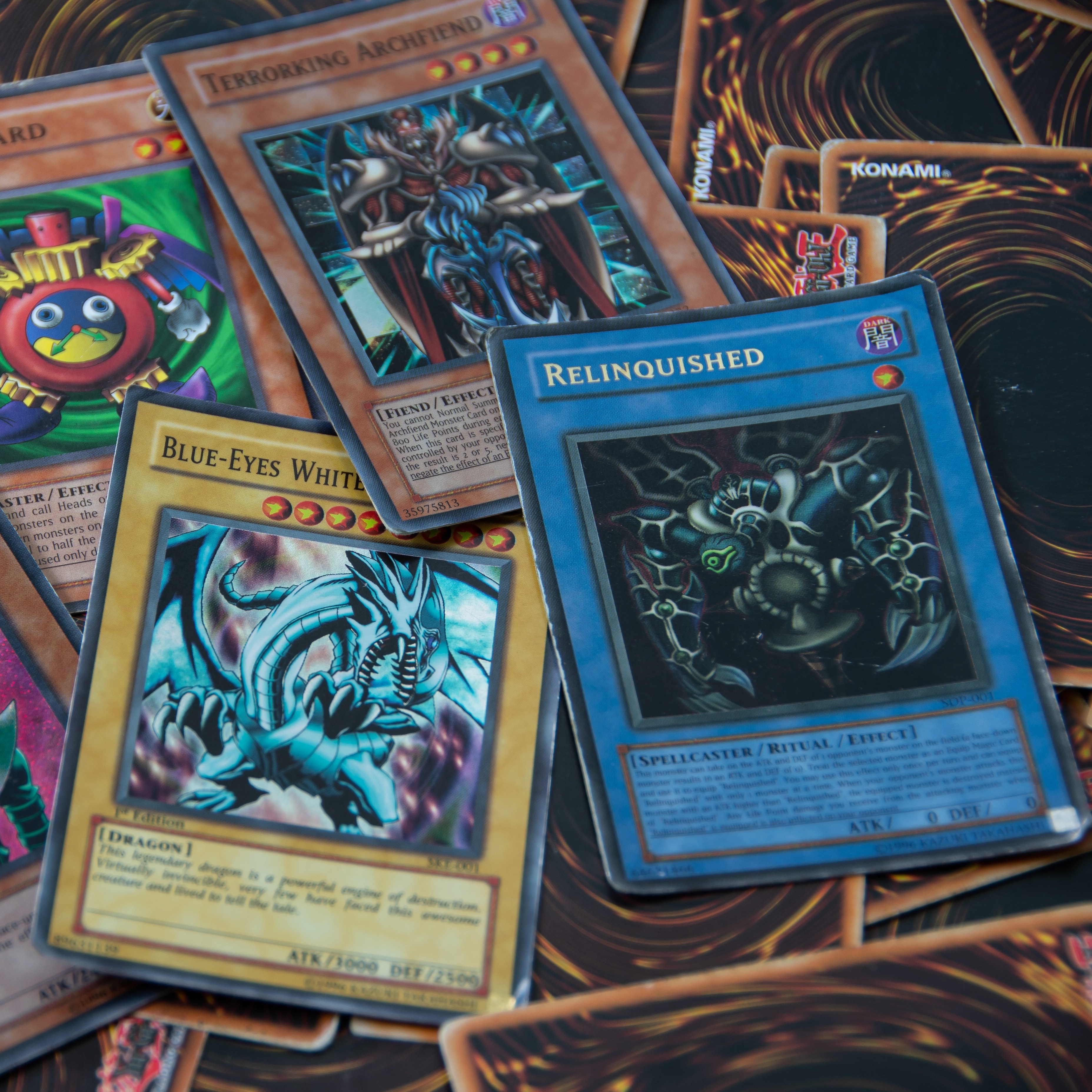 A close up of a few face-up Yu-Gi-Oh! cards spread across a pile of cards on a flat surface.