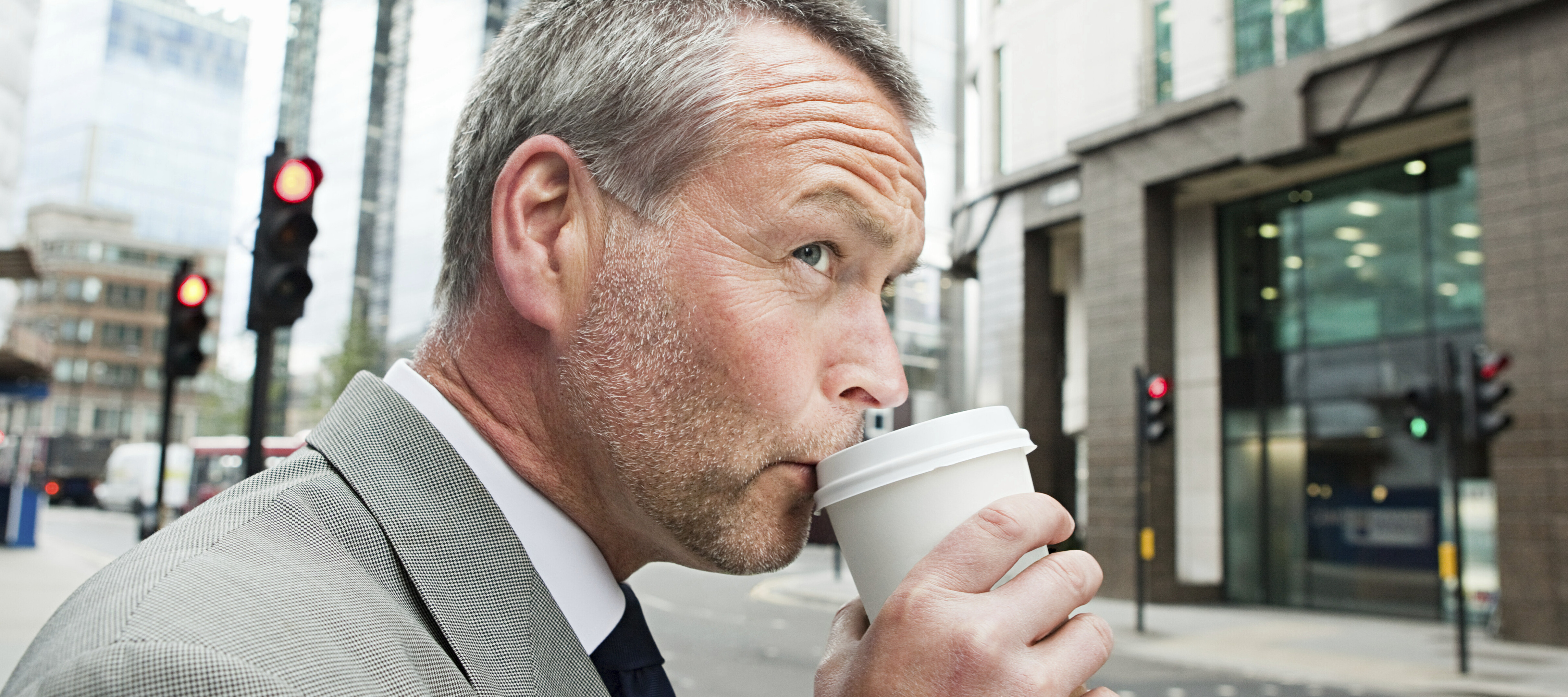 Man drinking coffee while crossing city street