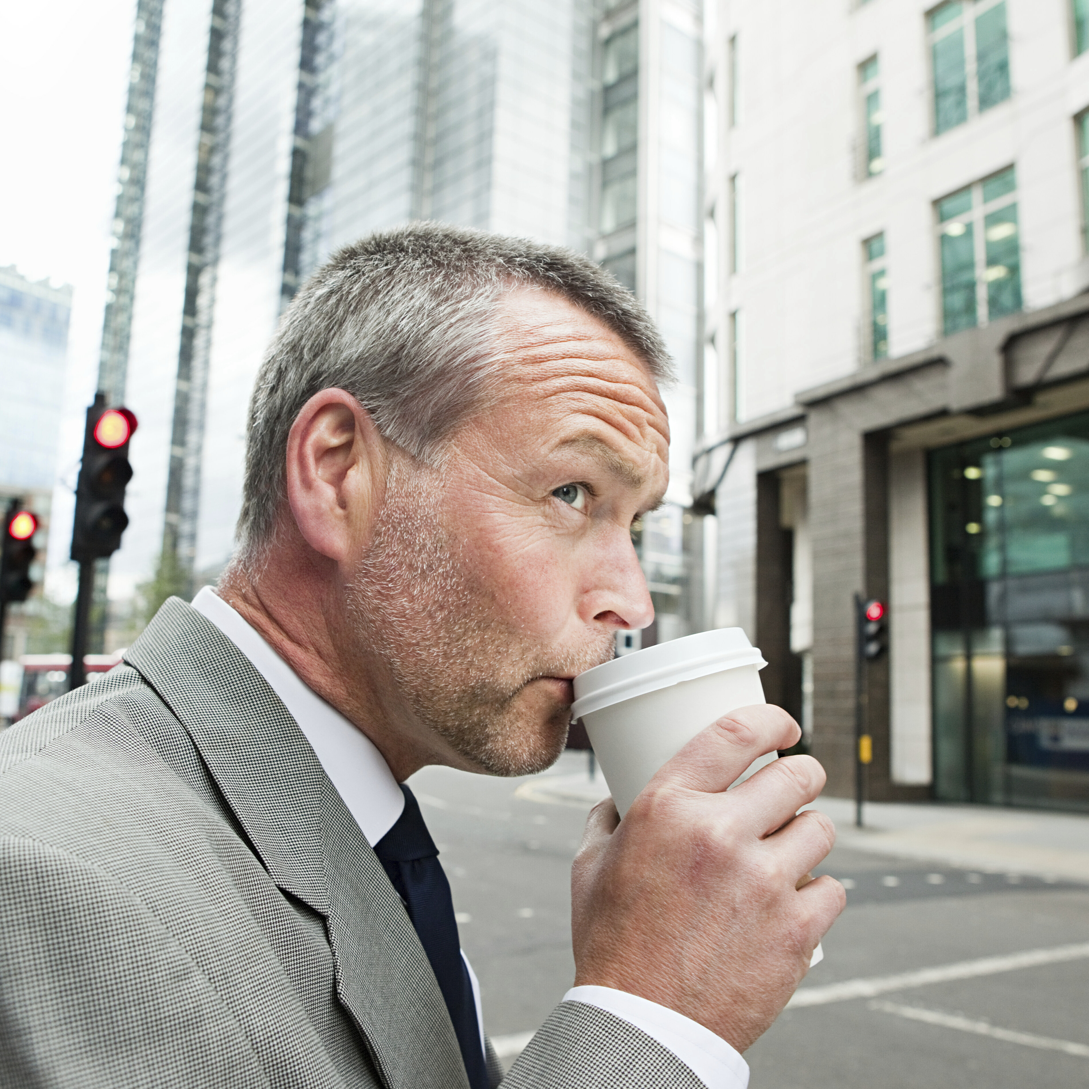 Man drinking coffee while crossing city street