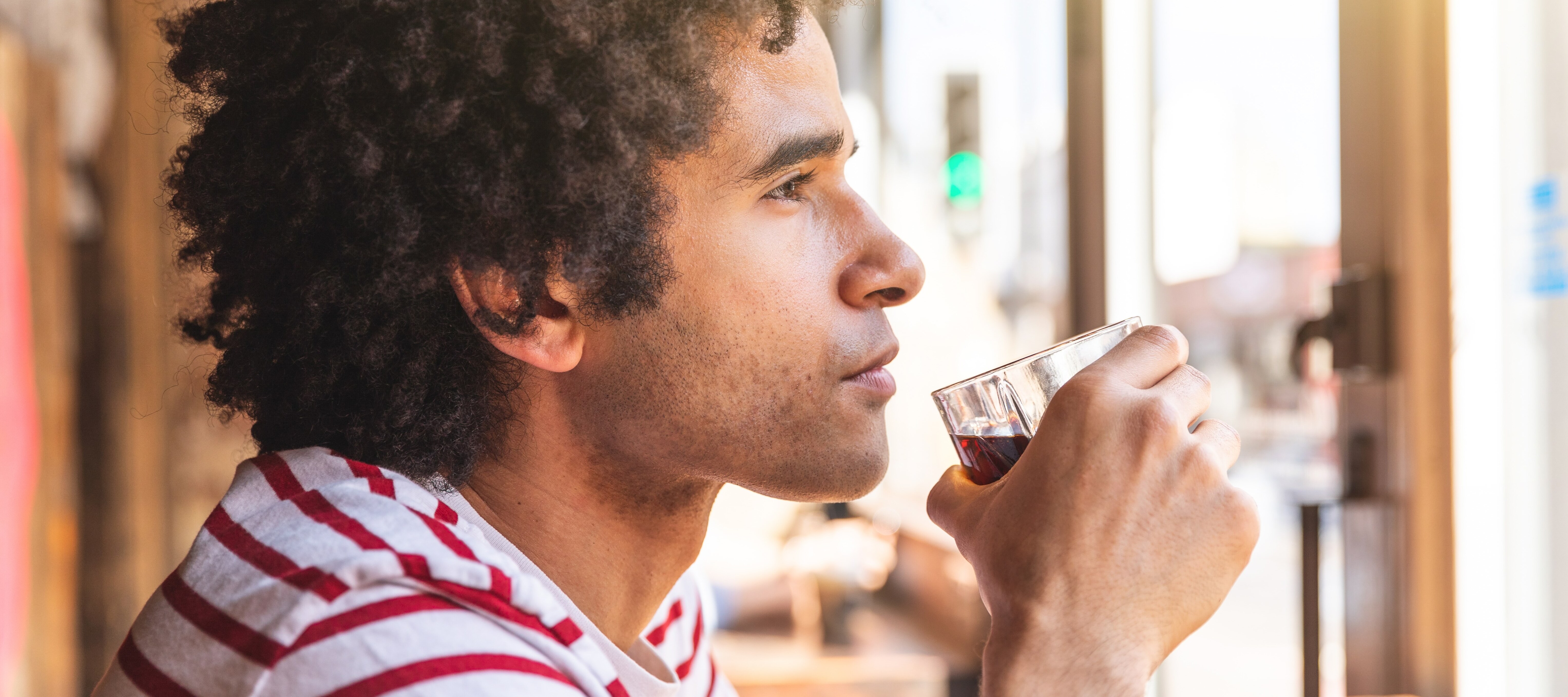 35-year-old man sipping a drink and looking out bar window