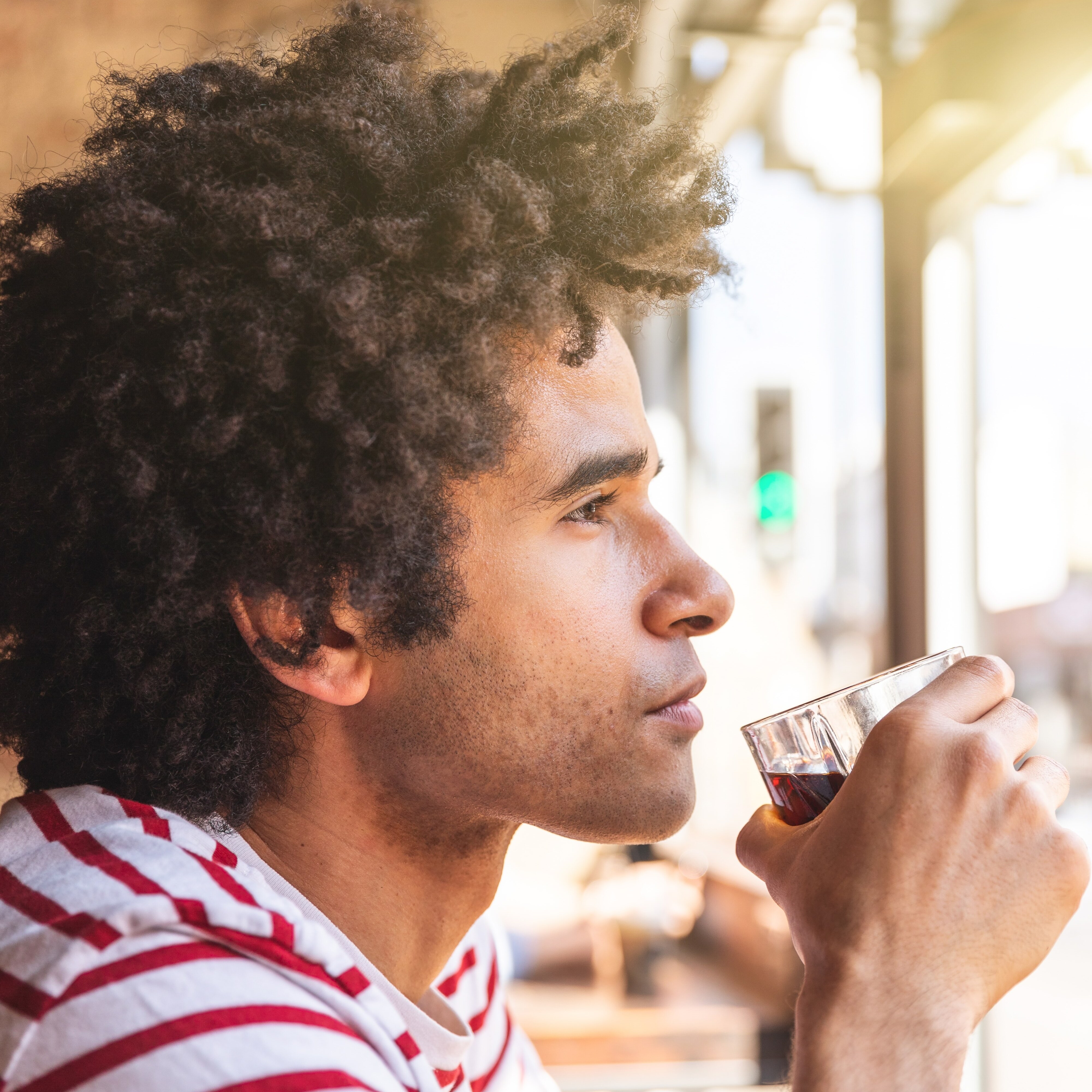 35-year-old man sipping a drink and looking out bar window