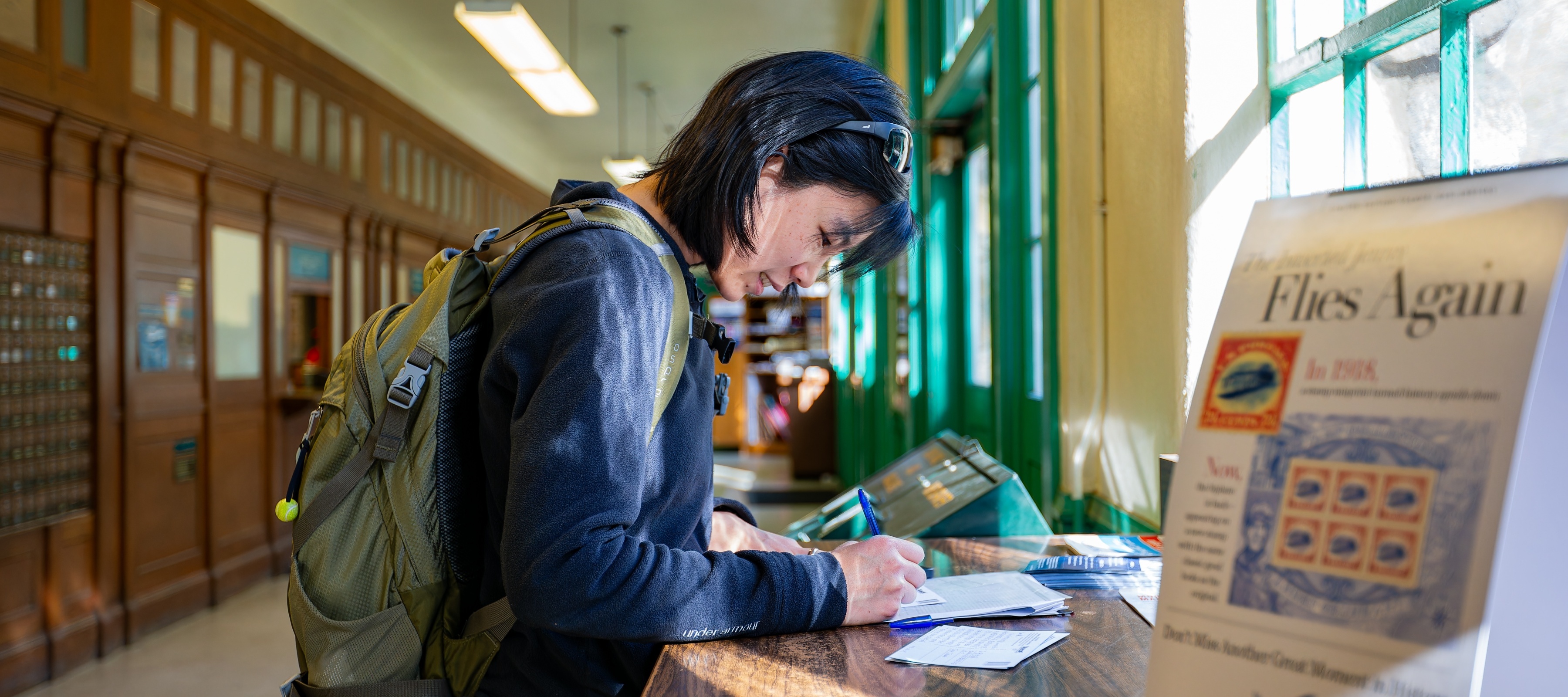 Interior view of the United States Postal Service at Yosemite as a woman fills out a form.