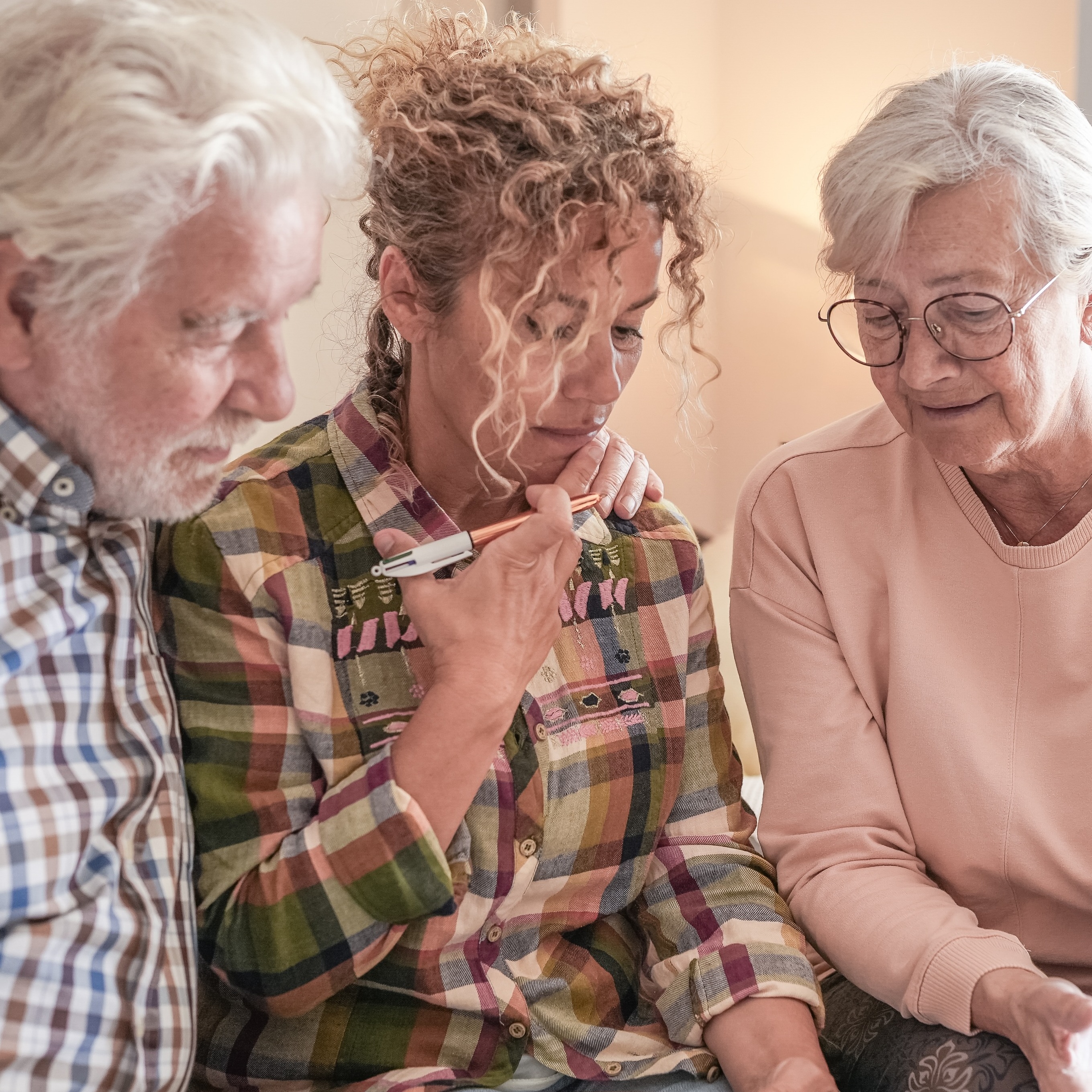 Retired couple sitting with their adult daughter, looking pensive
