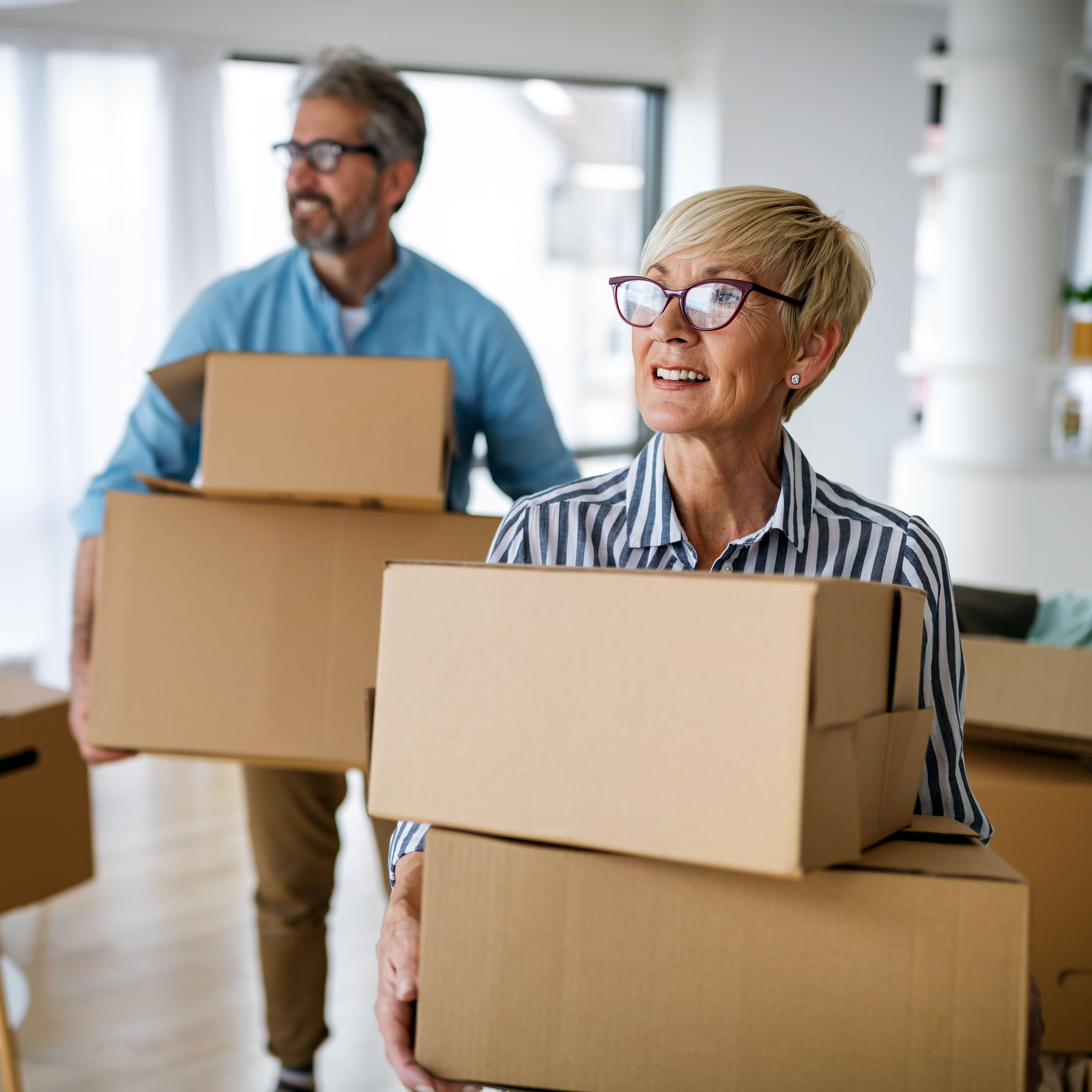 A mature couple hold moving boxes in their new home.