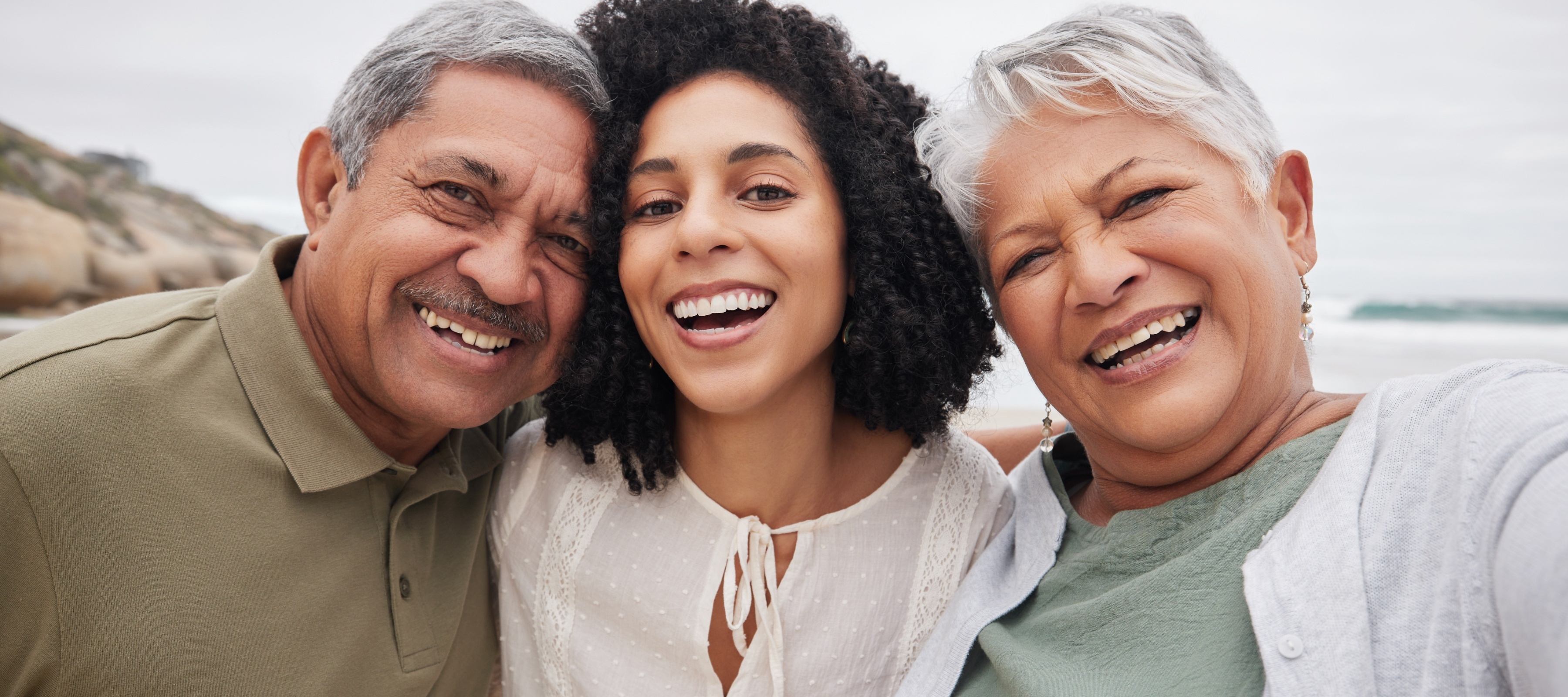 A retired couple smiles on the beach with their daughter but their wealth may one day be transferred to long-term care costs instead of family