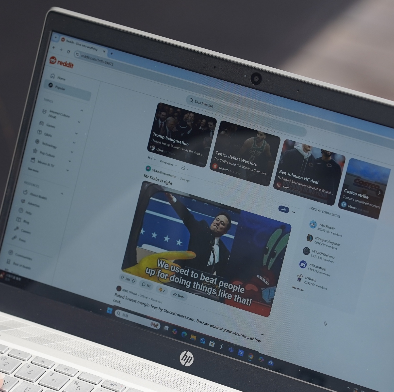 An over-the-shoulder view of a woman using Reddit on her laptop