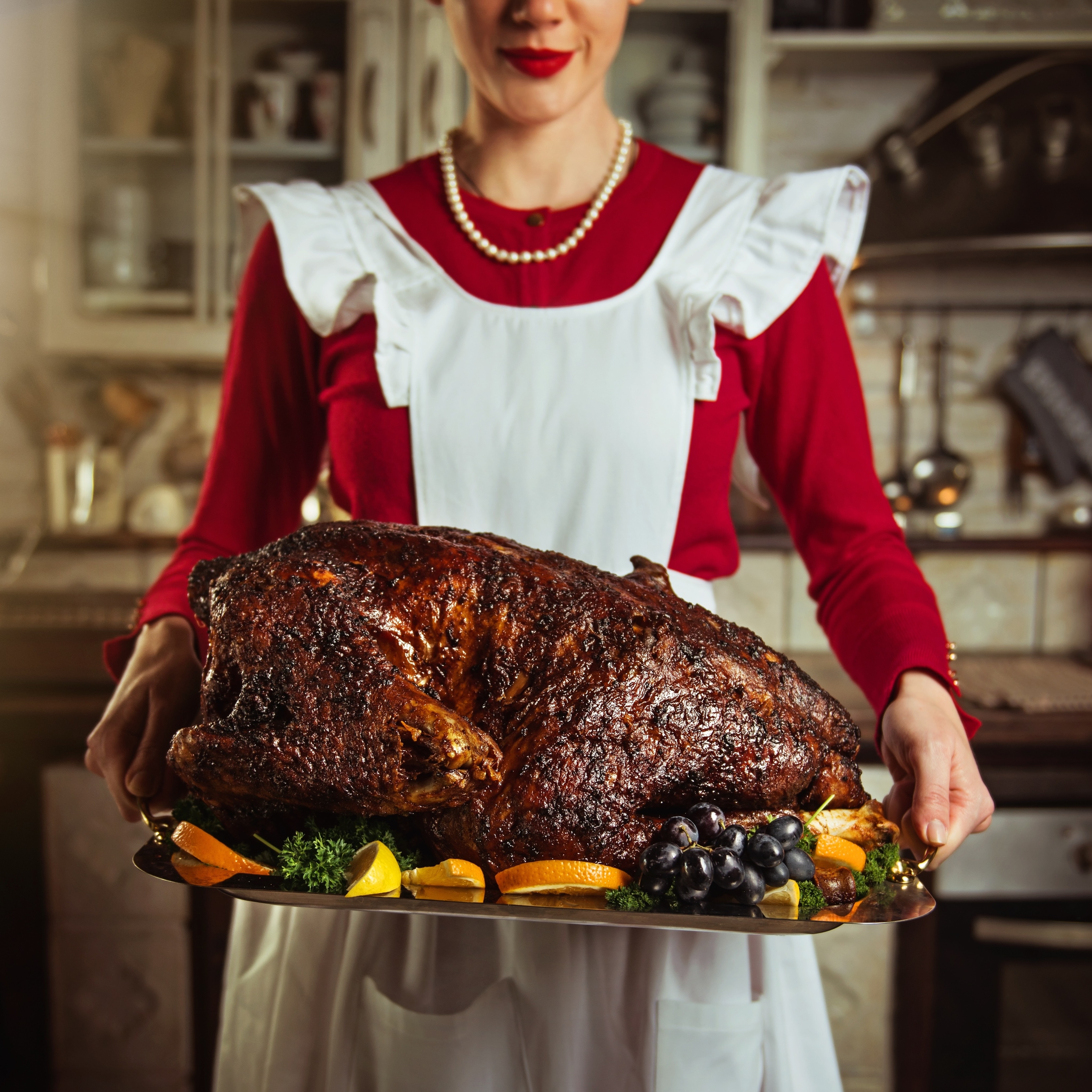 A trad wife holding a traditional turkey dinner roast.