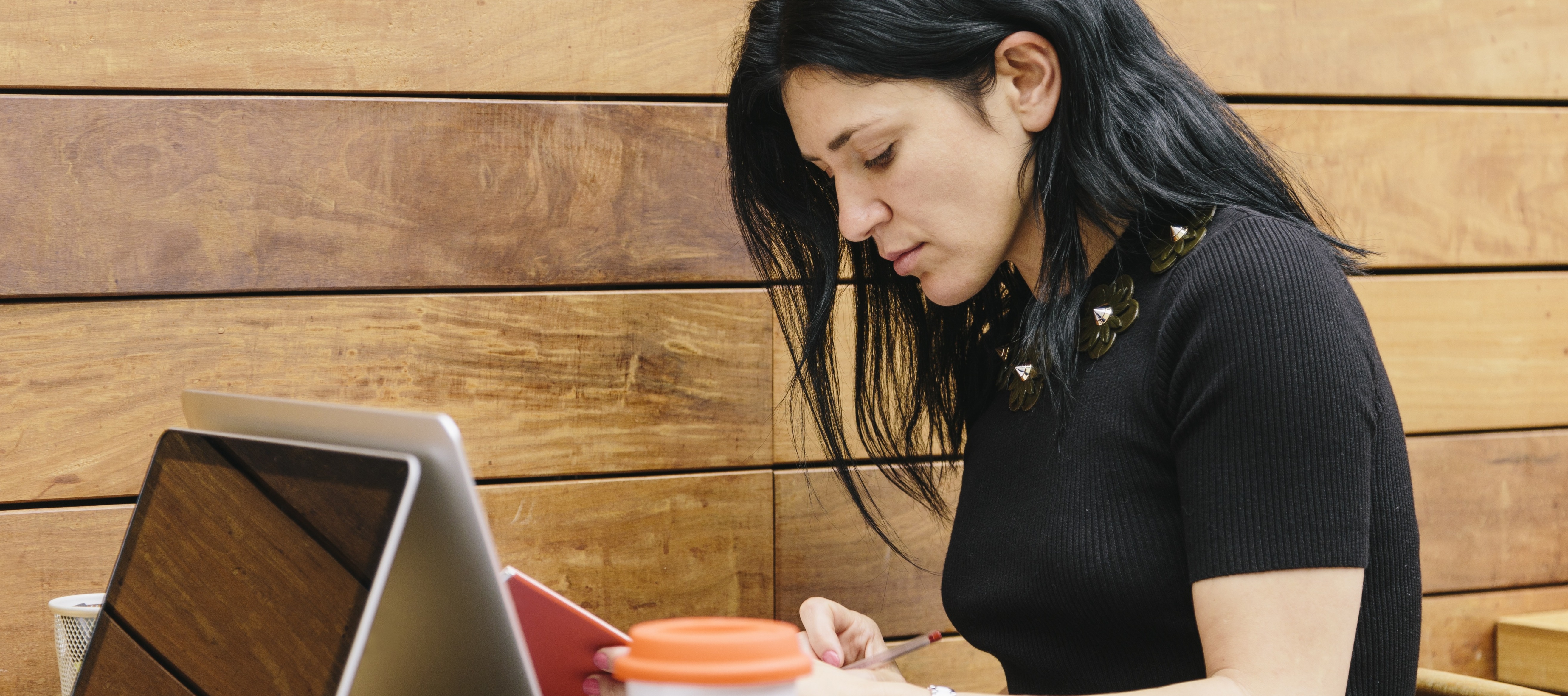 Young woman writing on laptop at coffee shop