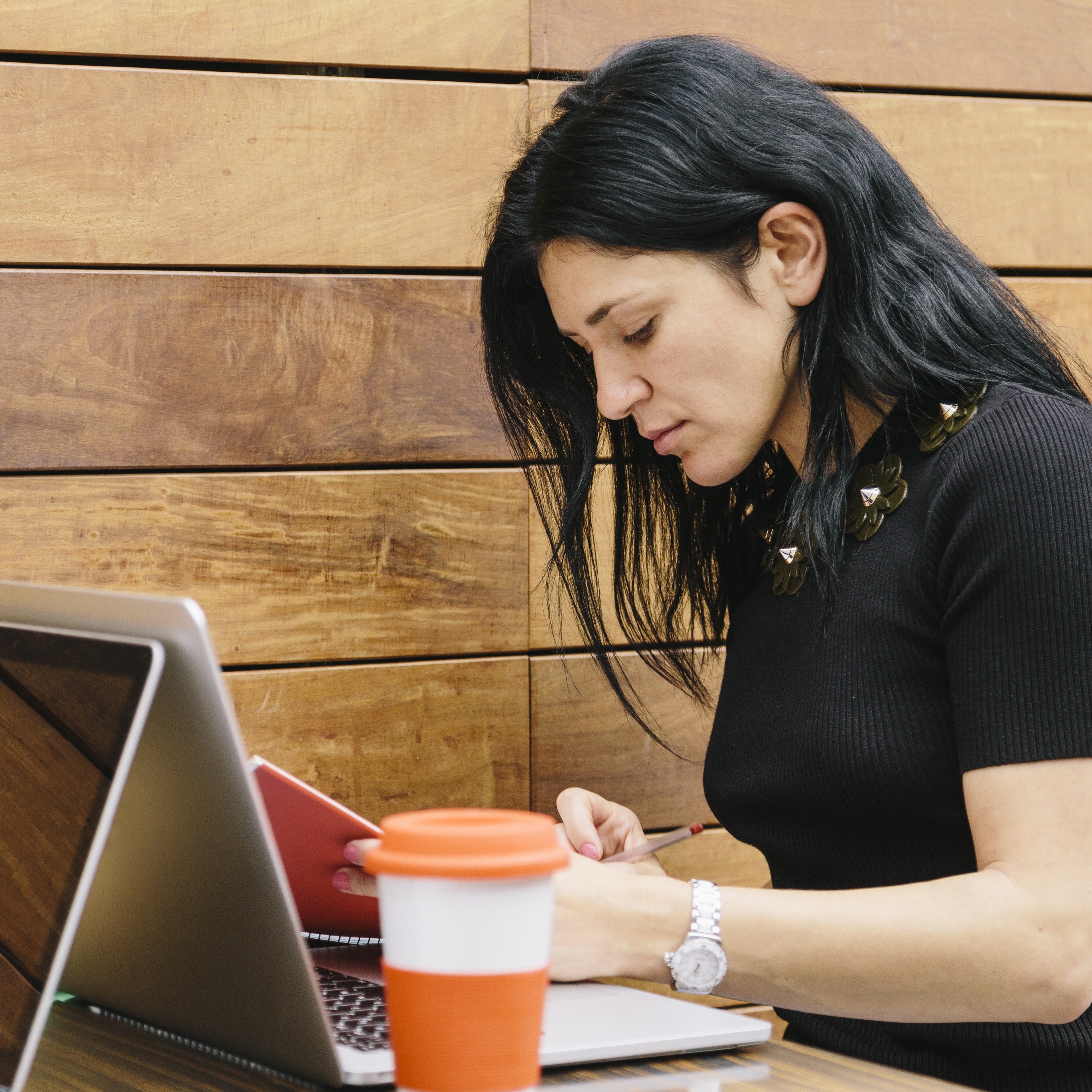 Young woman writing on laptop at coffee shop