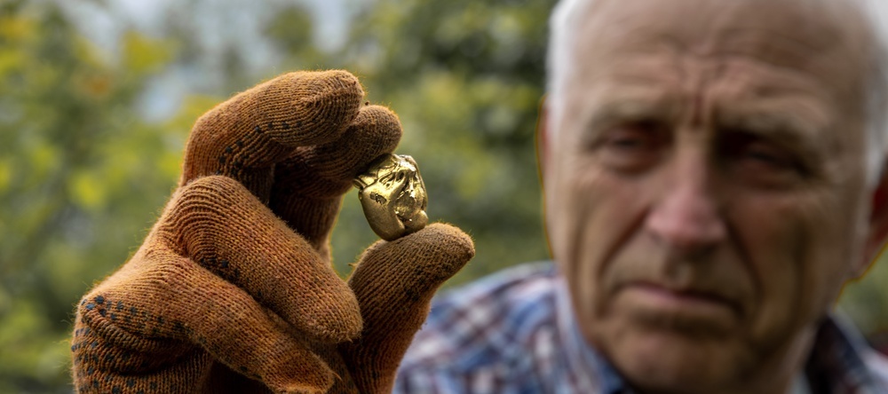 A photo of an elderly man holding a nugget of gold