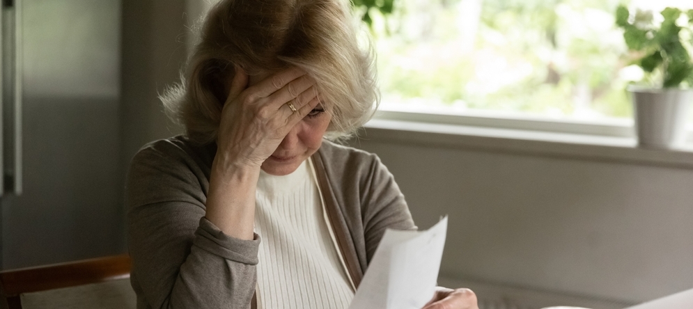 Photo of an older worker at a desk, looking stressed