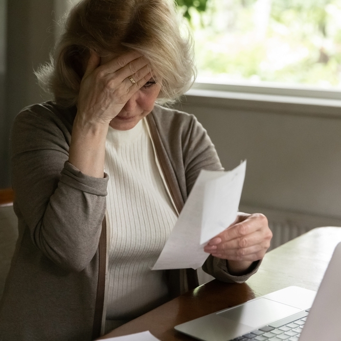 Photo of an older worker at a desk, looking stressed