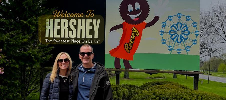 Lisa and Matt stand in front of sign in Hershey Pennsylvania.