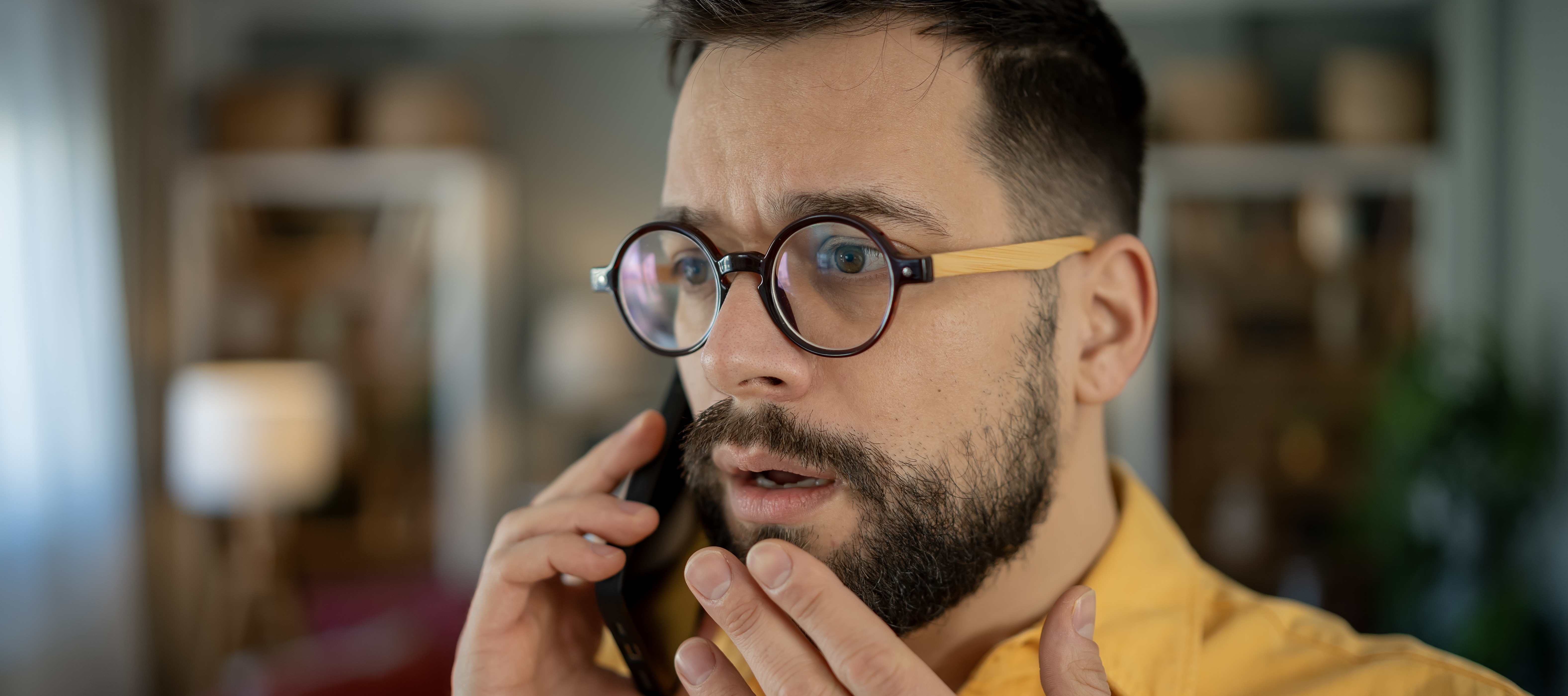A millennial man is on the phone expressing concern.