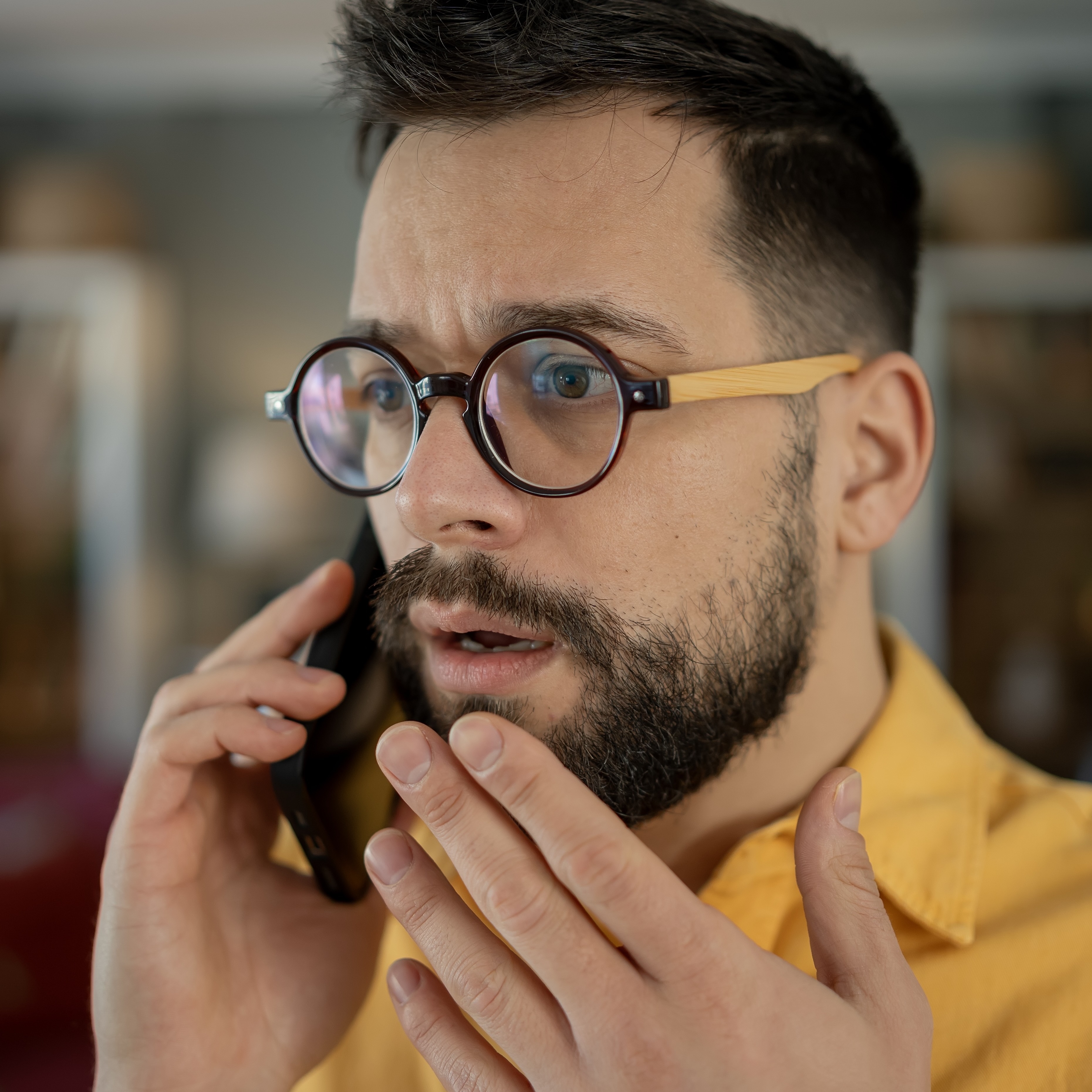 A millennial man is on the phone expressing concern.