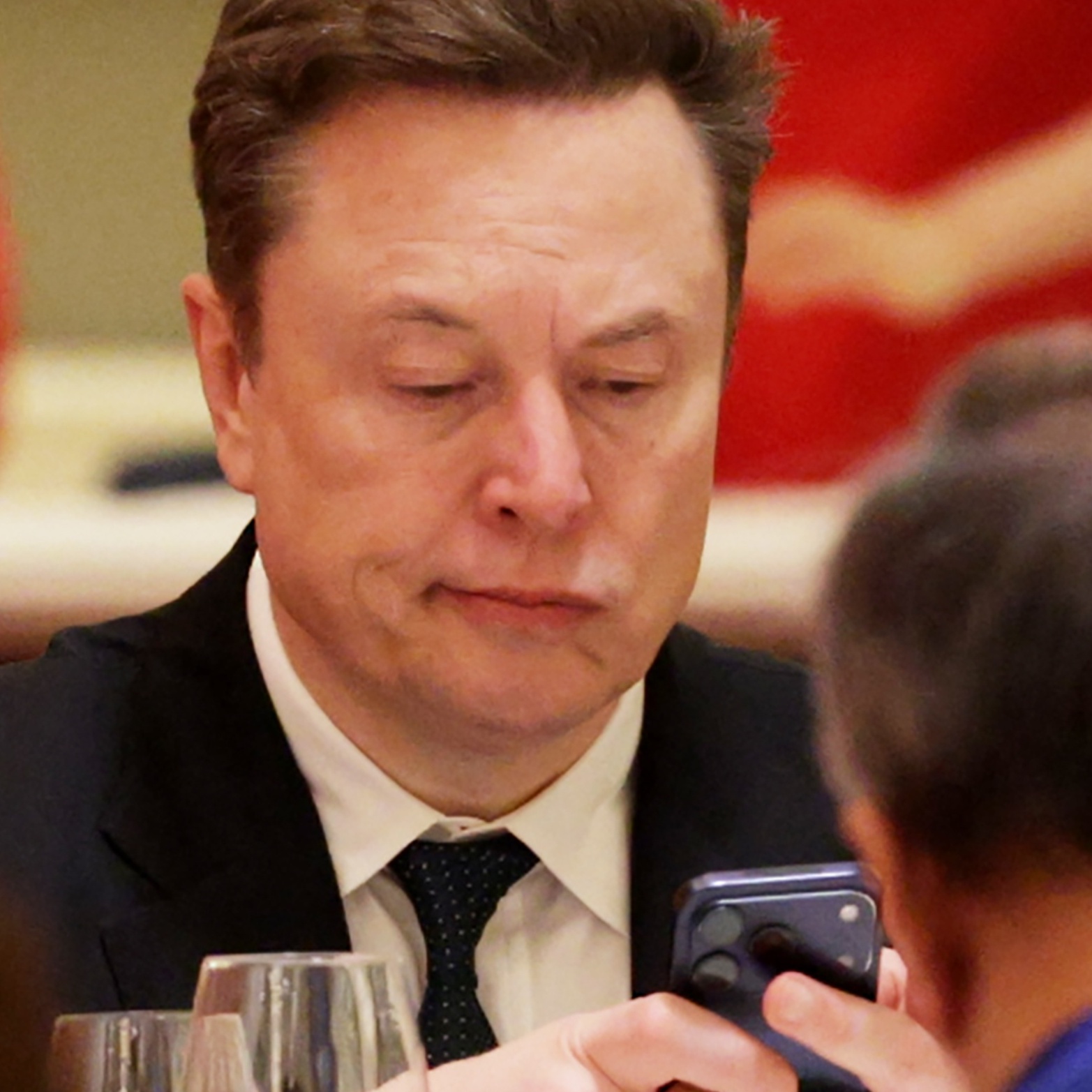 A composite shot of Elon Musk a state banquet hosted by Chinese President Xi Jinping and an unrelated image of the Grok website seen on a computer screen.