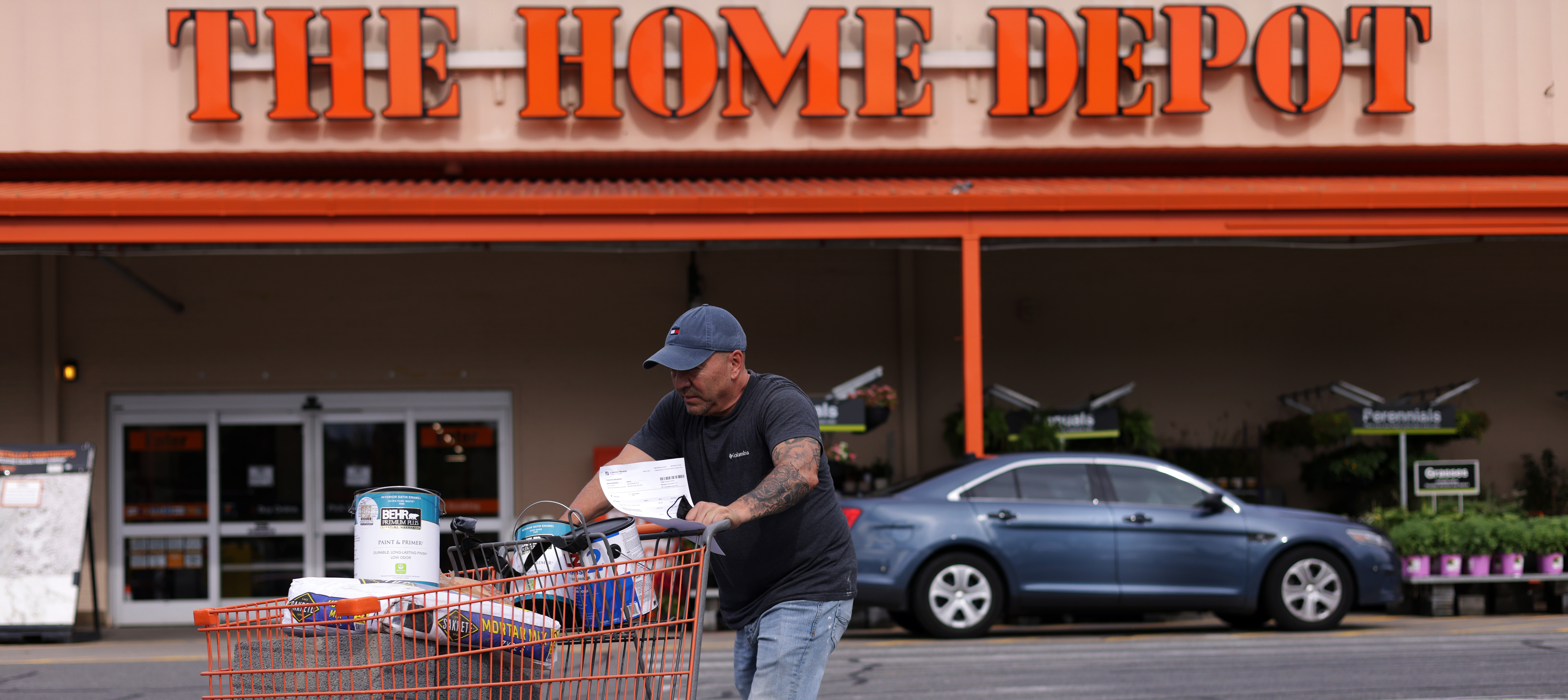 A shopper leaves a Home Depot with merchandise in a shopping cart.