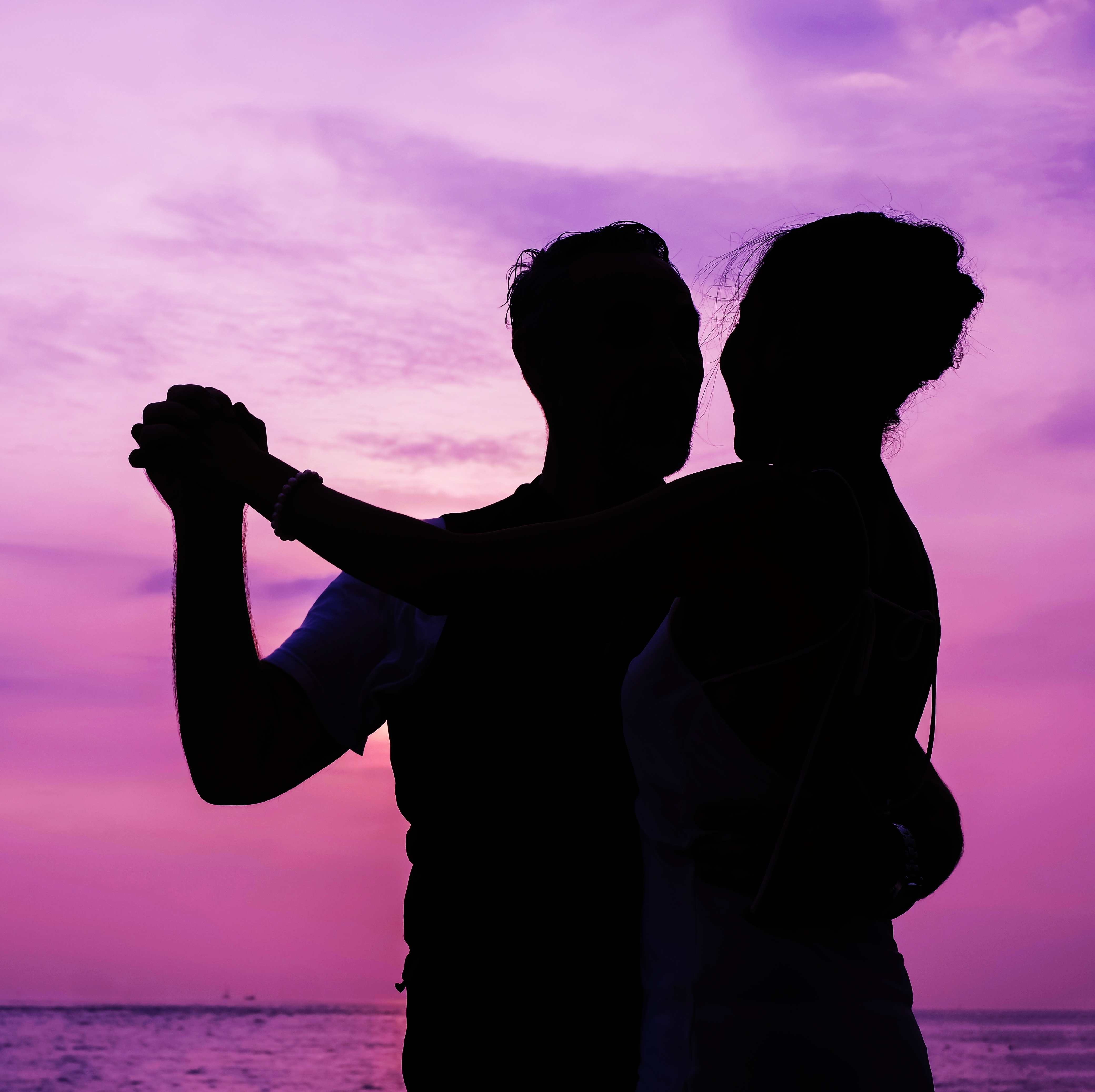 The silhouette of a couple dancing on the beach at night.