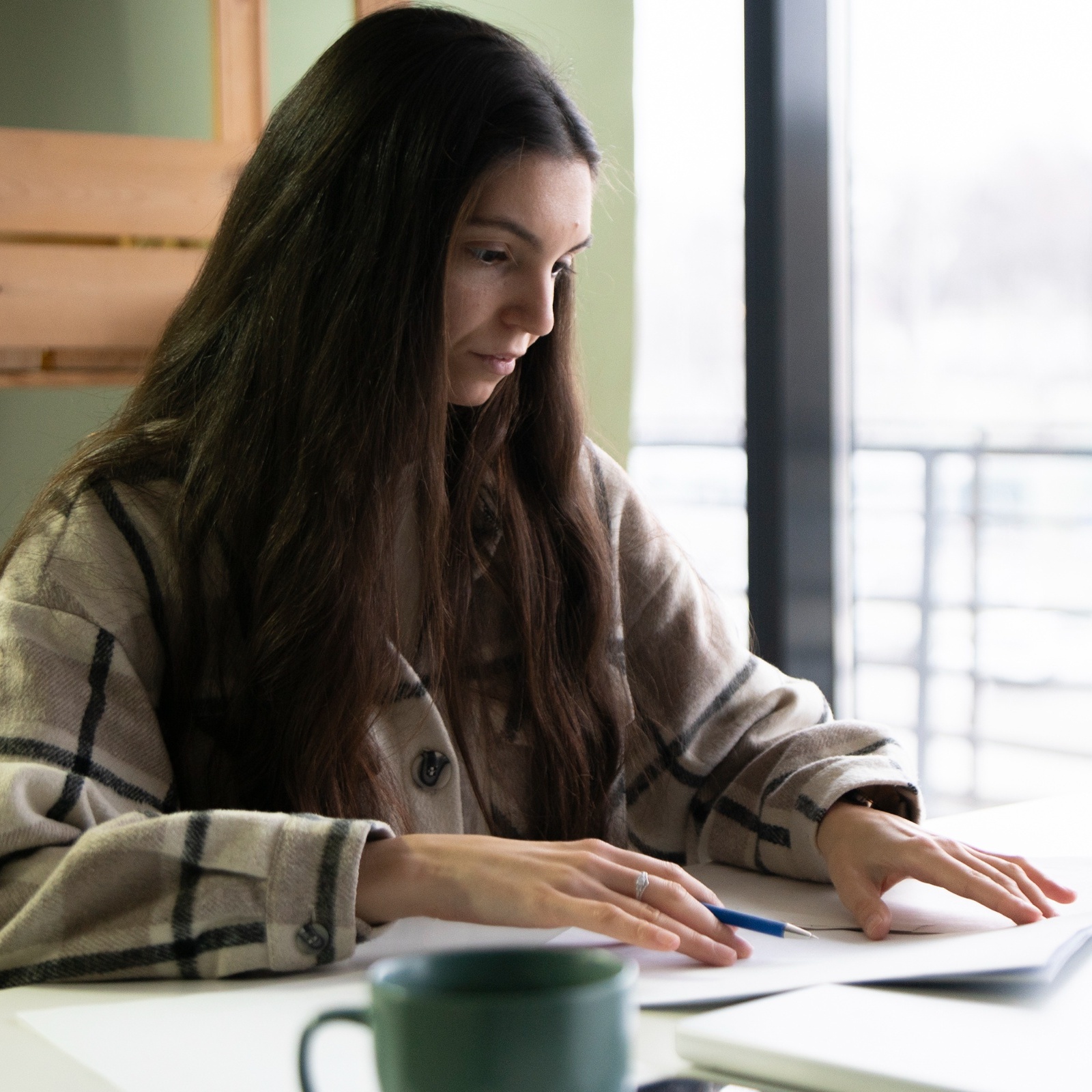 L: Young woman working at laptop, R: Stripe Financial Services app displayed on phone screen
