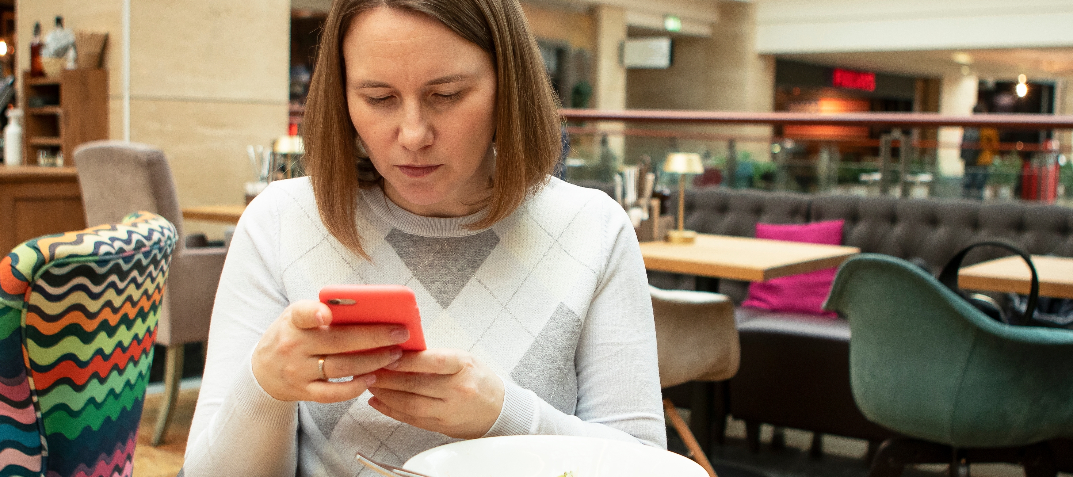 Young woman concernedly looking at phone while eating meal