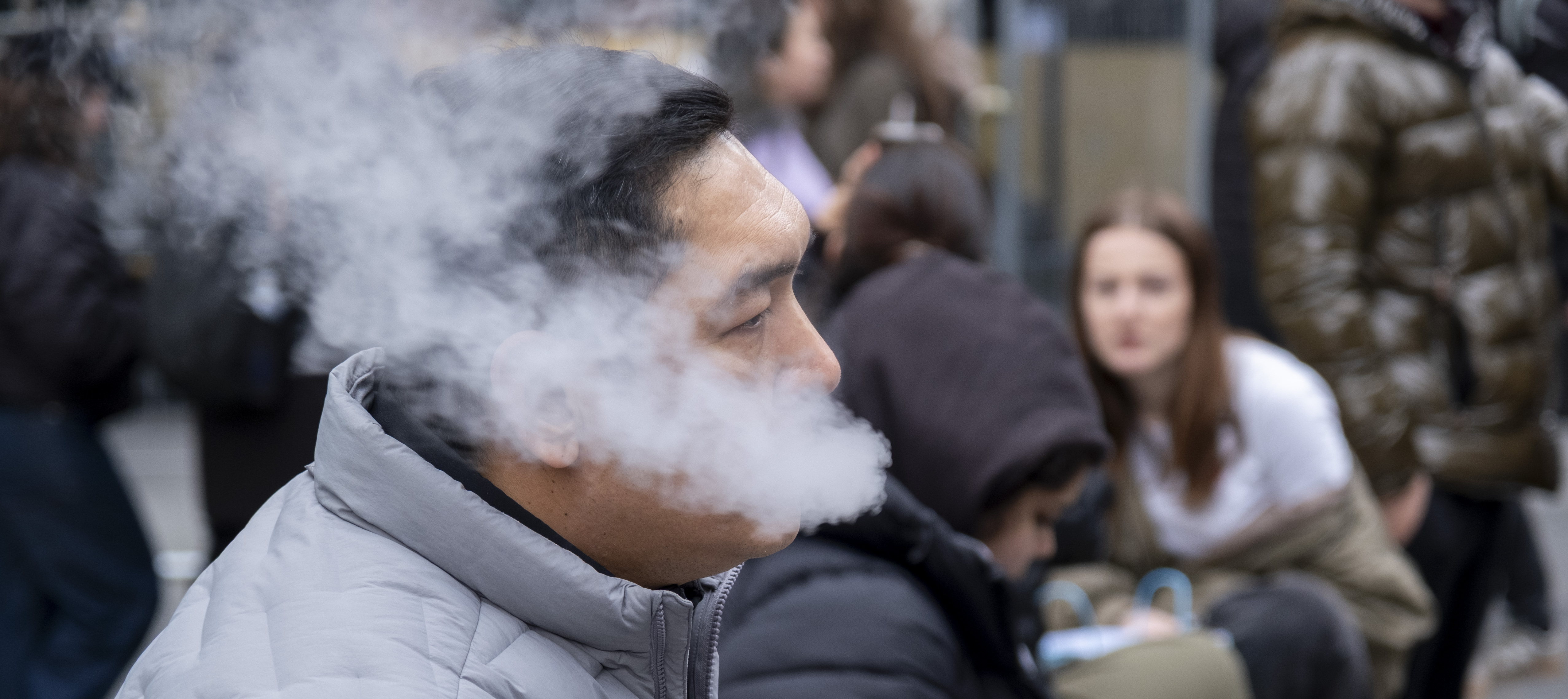 A man vaping on the street.