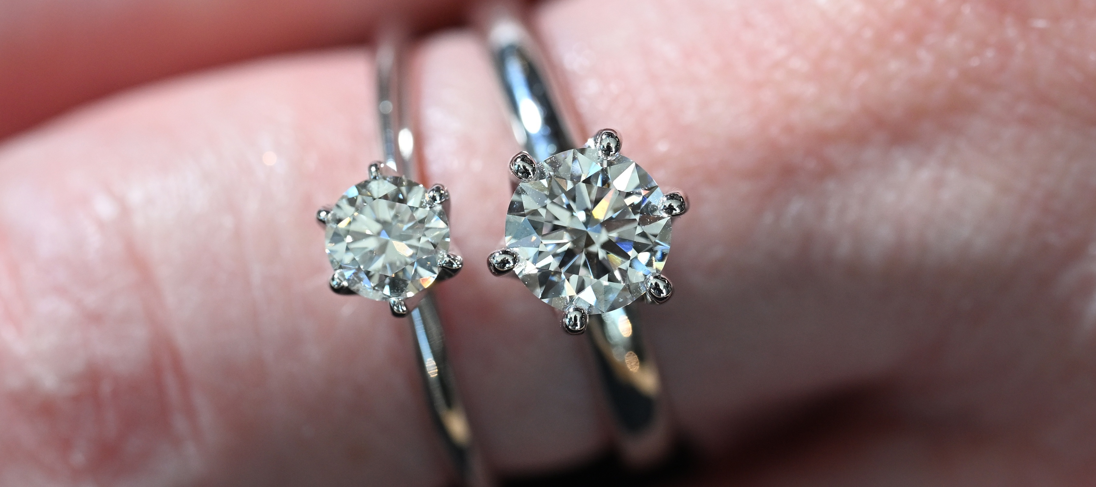 A close-up of a woman's hand wearing two diamond engagement ring