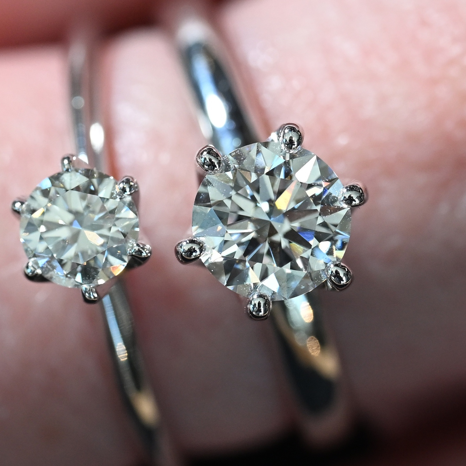 A close-up of a woman's hand wearing two diamond engagement ring