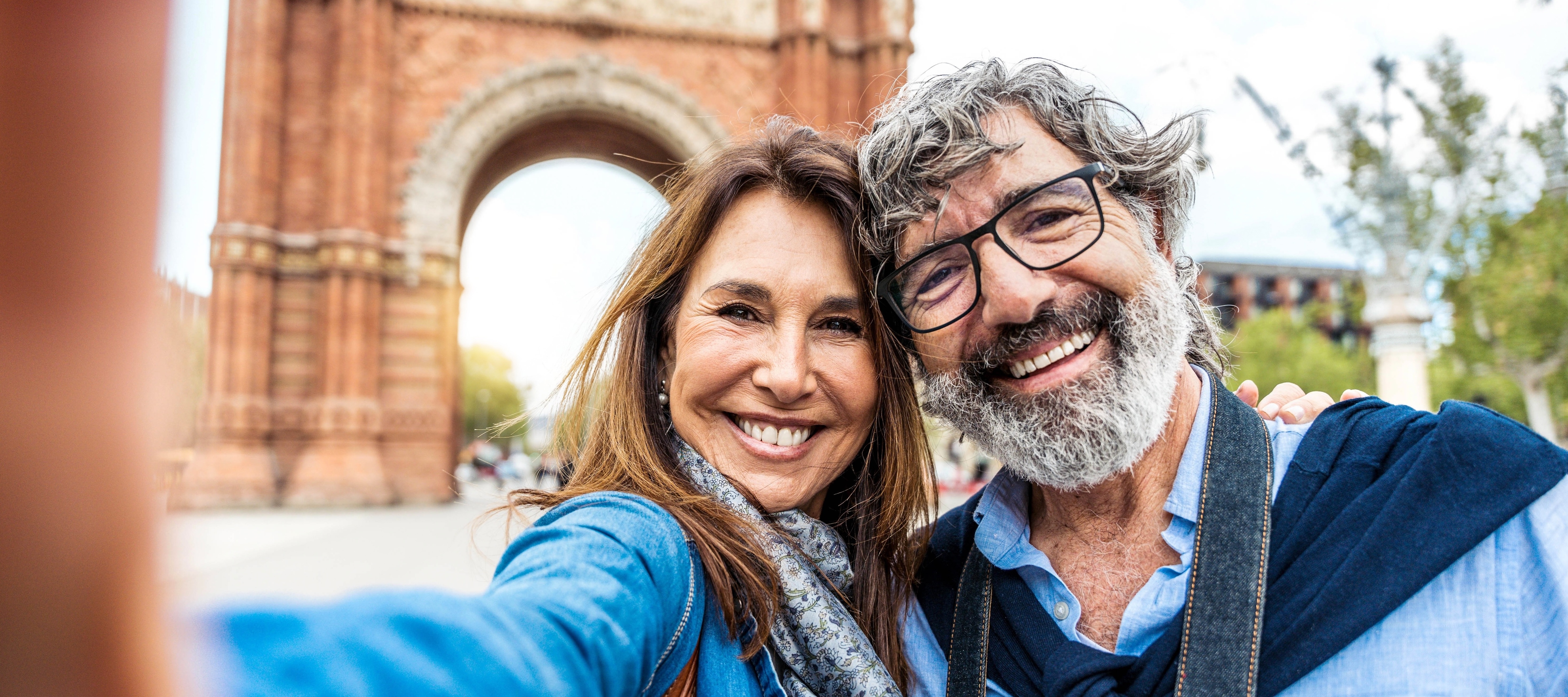 Married older happy couple taking selfie in front of Triumphal Arch in Barcelona, Catalonia, Spain.