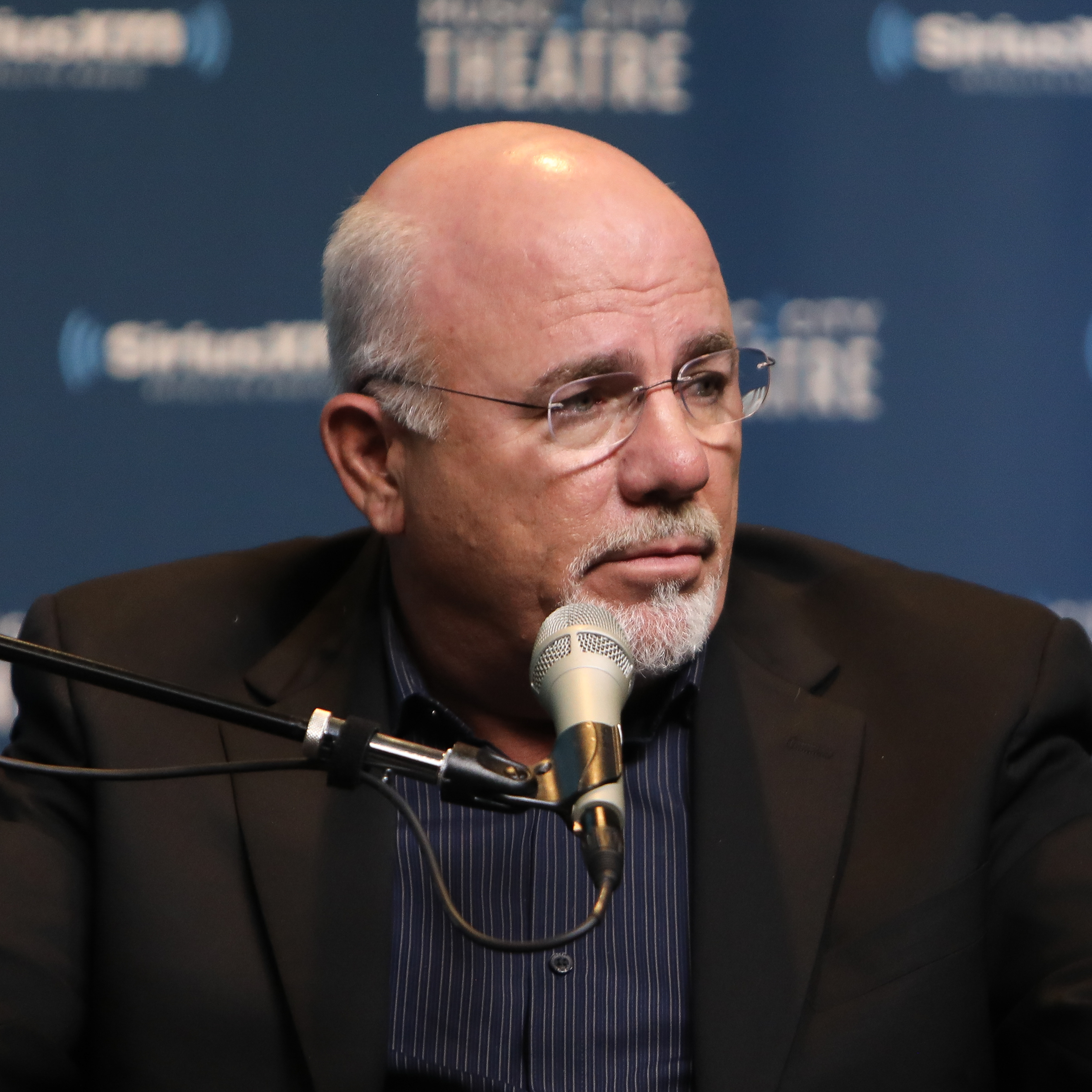 Dave Ramsey spreads both his hands out on stage, questioningly.