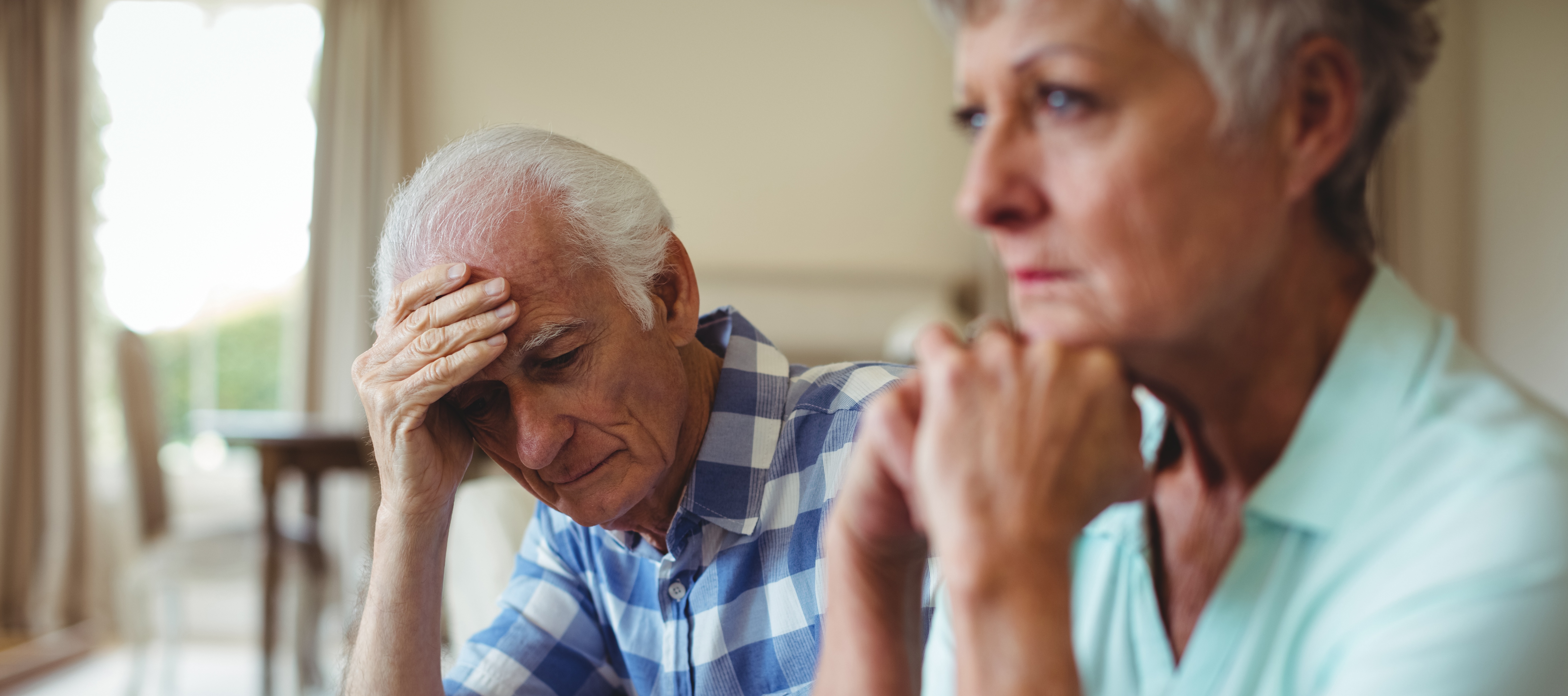 An older worried couple sits together.