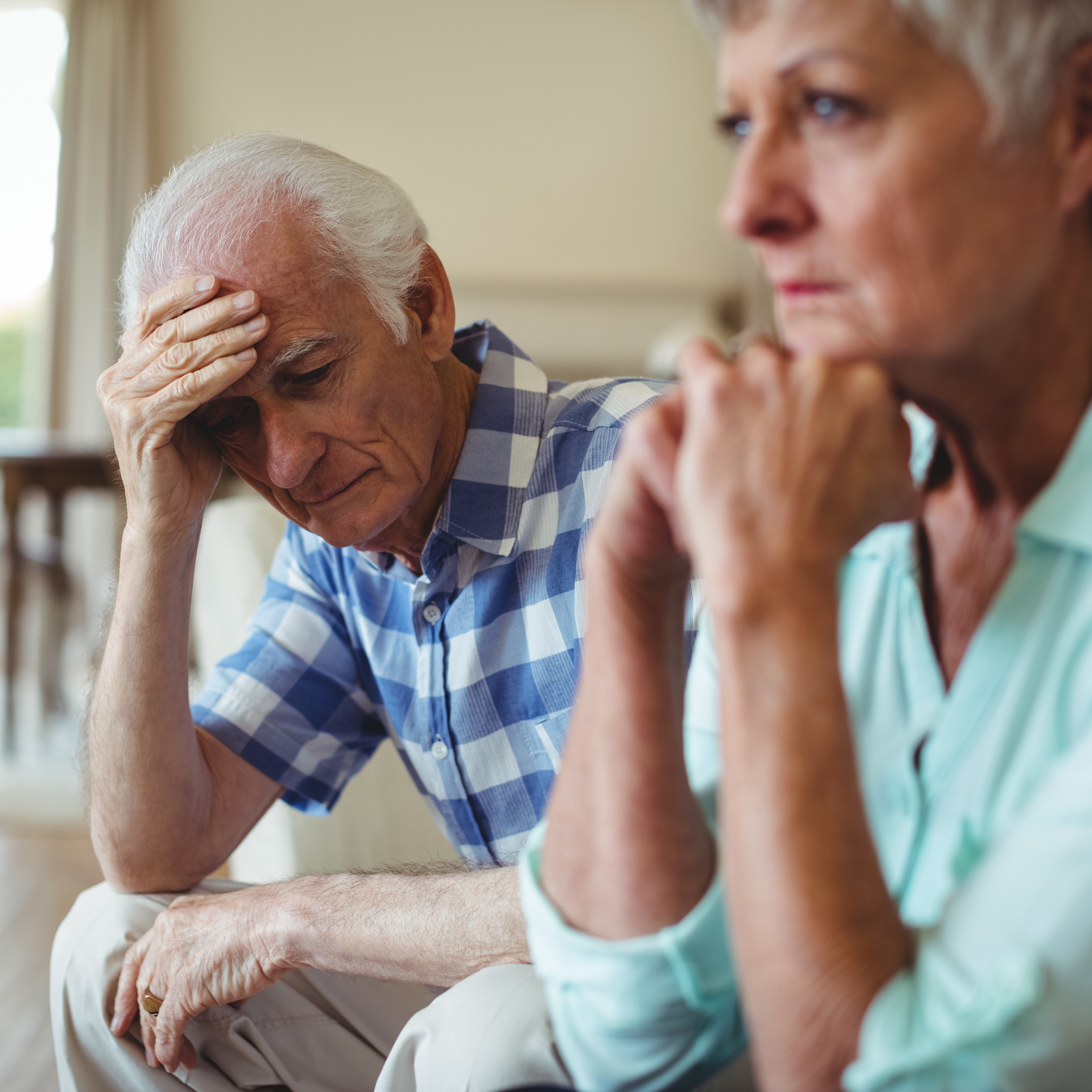 An older worried couple sits together.