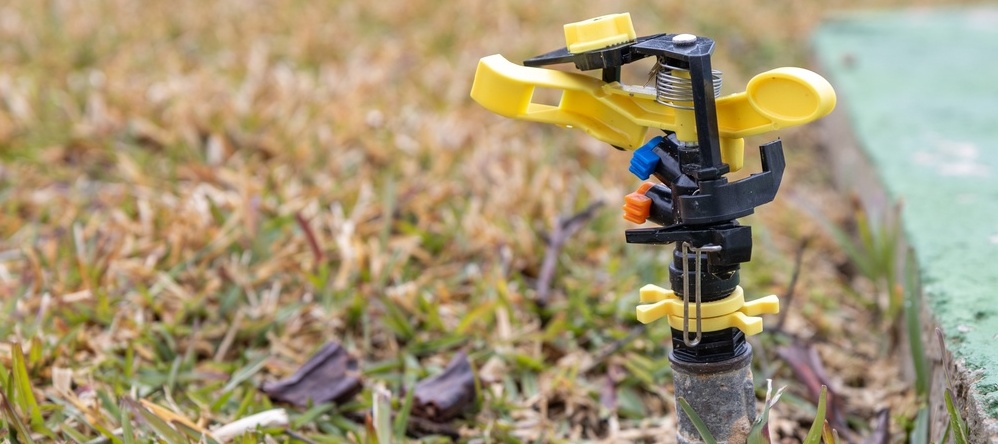 A photo of a sprinkler on a yellow lawn