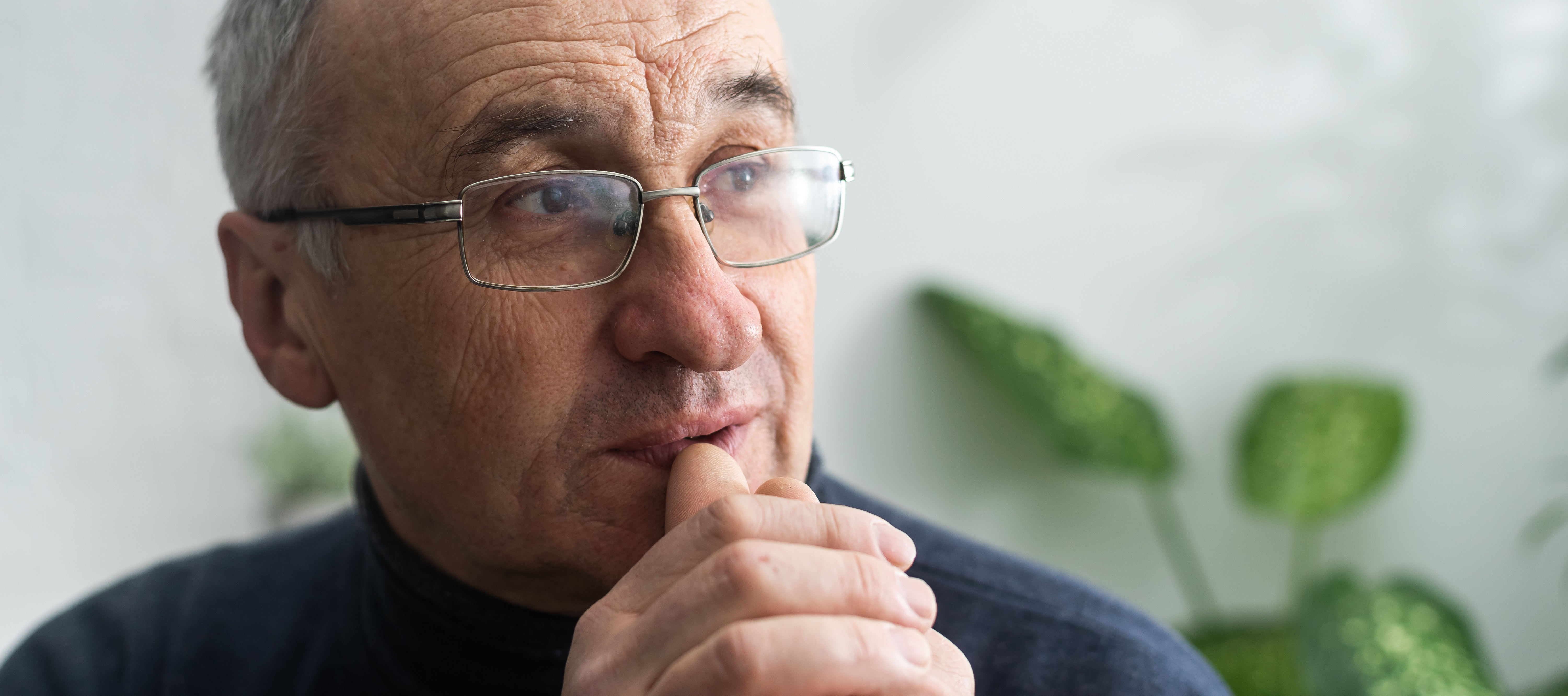 Man wearing glasses contemplating.