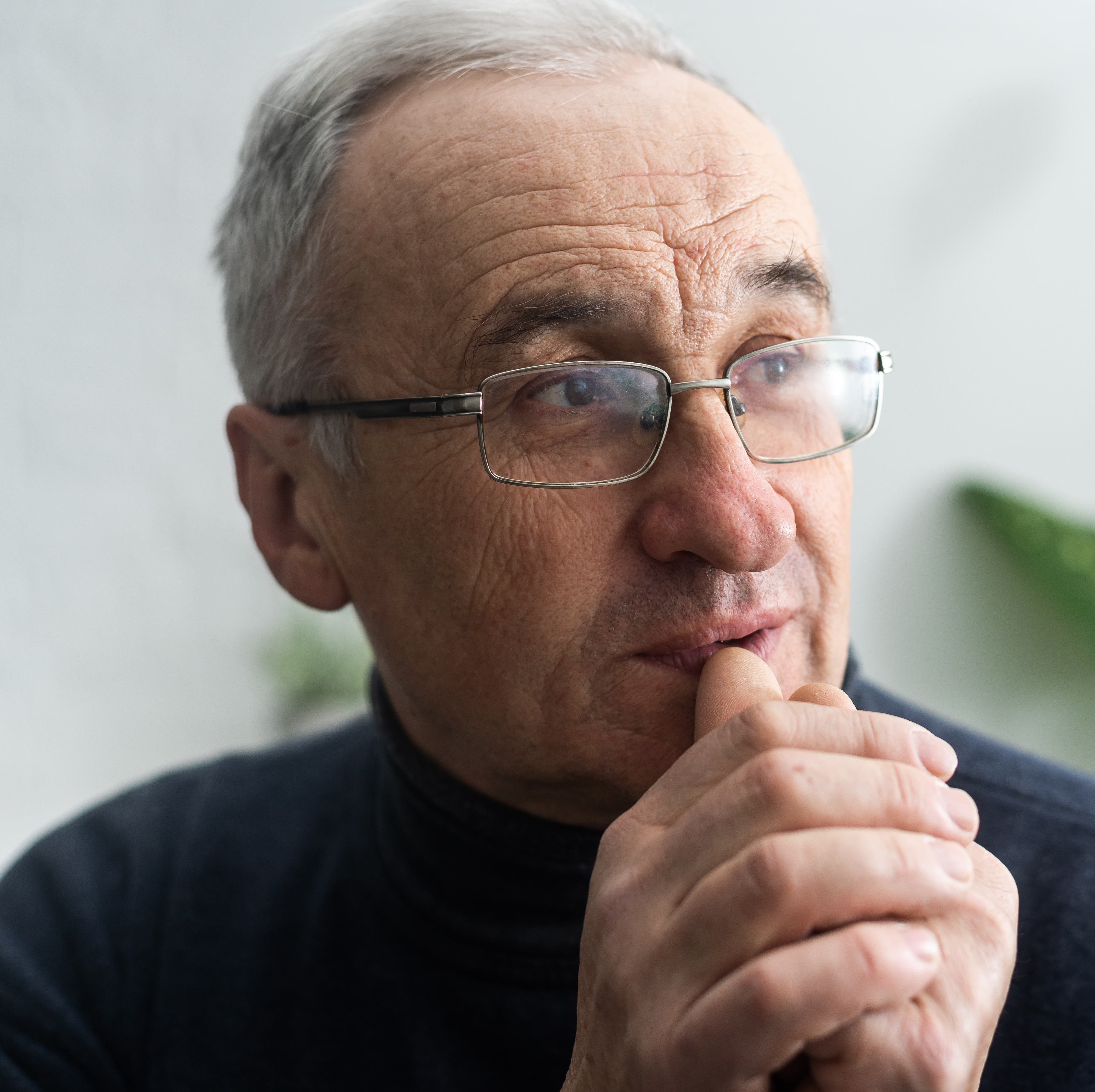 Man wearing glasses contemplating.