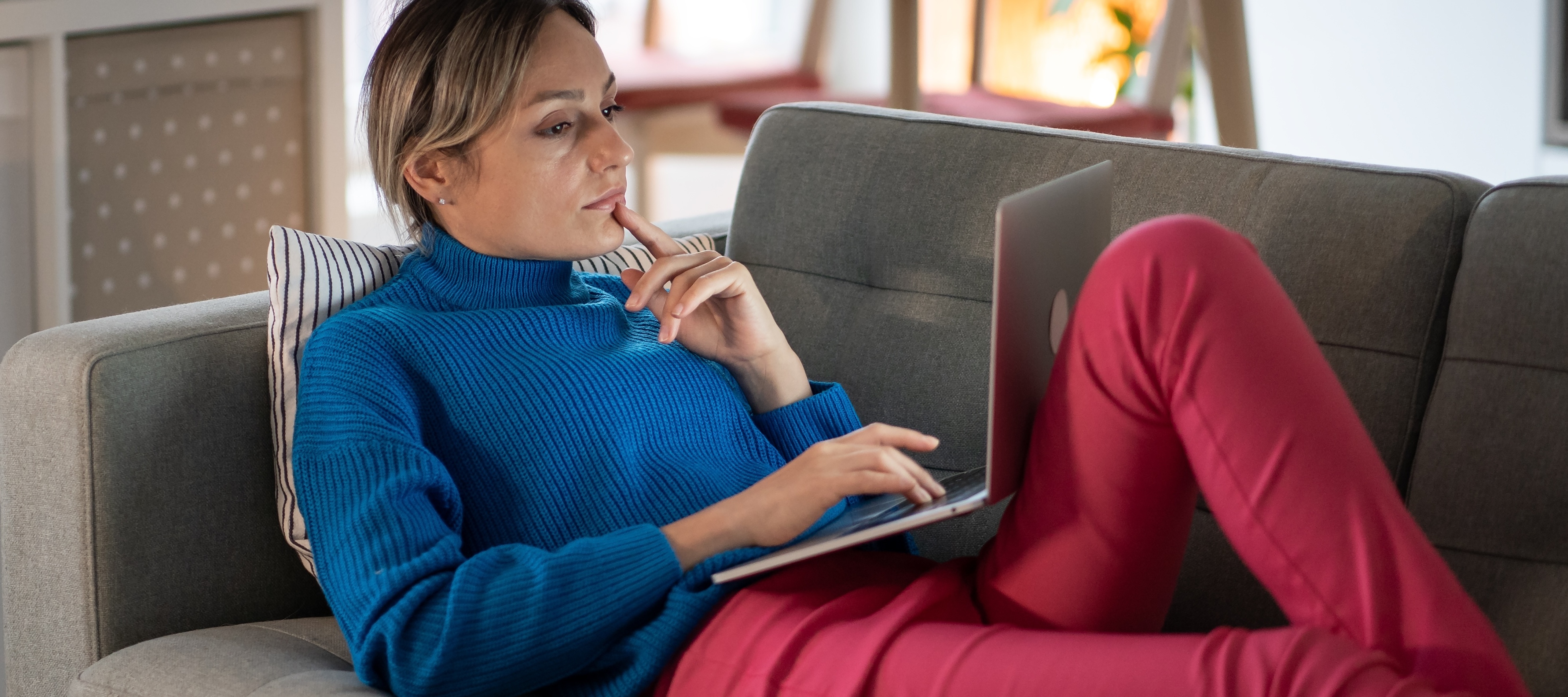 Woman looking at laptop while lounging on couch