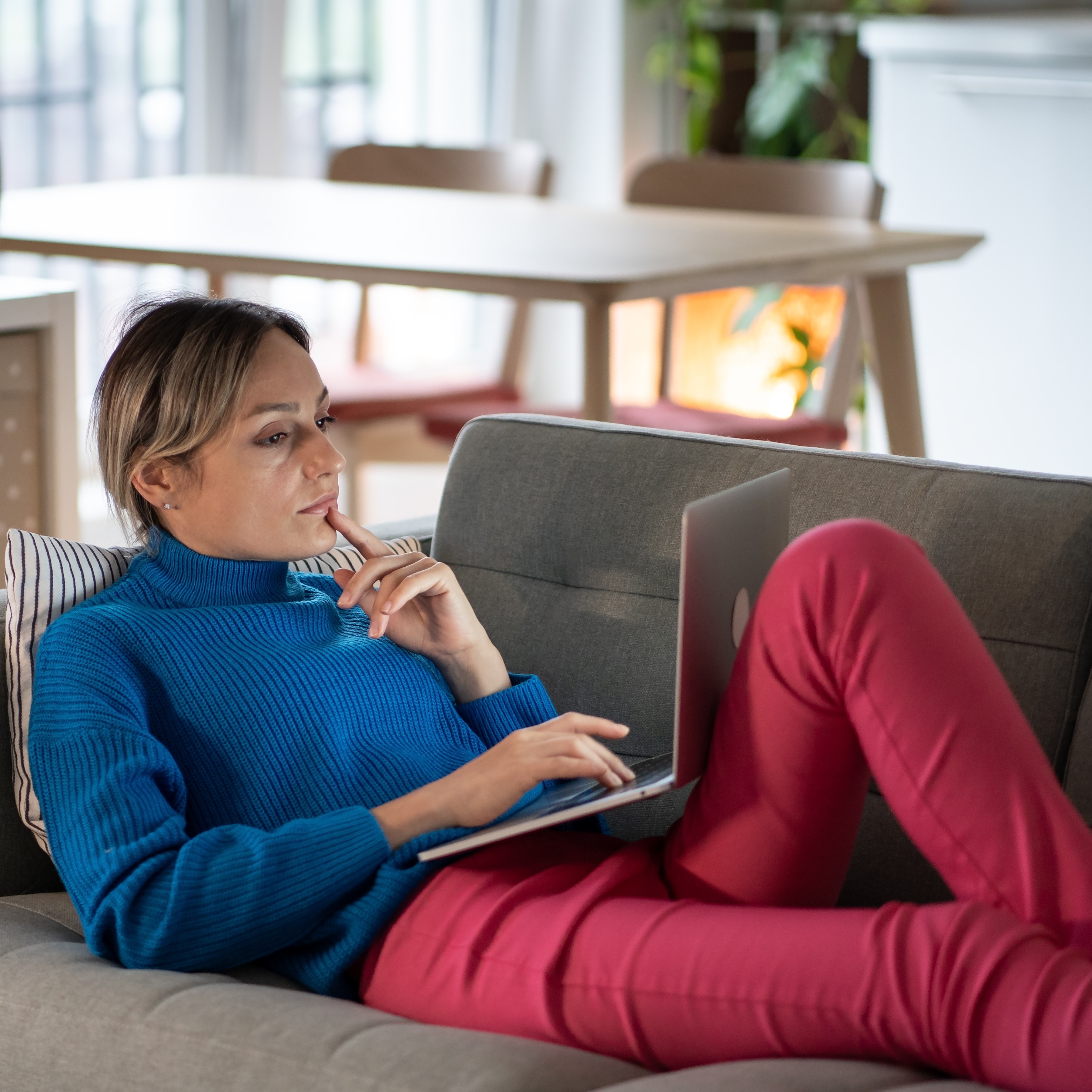 Woman looking at laptop while lounging on couch